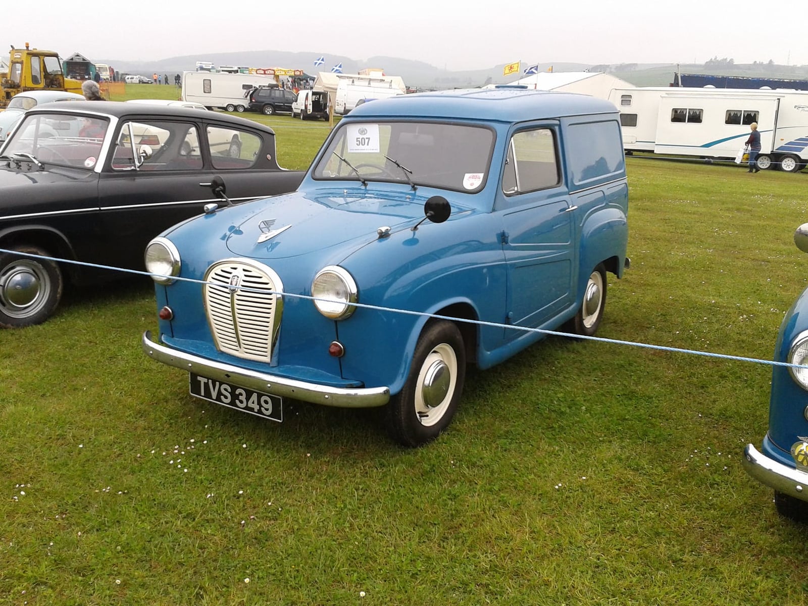 A blue 1960 Austin A35 van at a classic car show, front three-quarter view, UK registration TVS 349