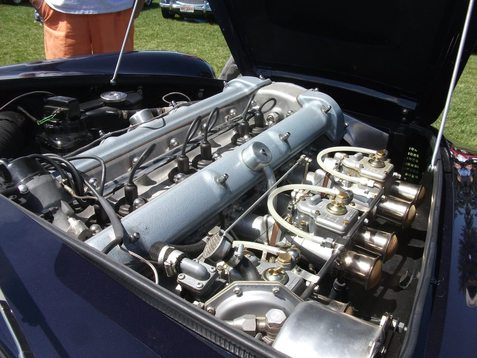 The engine bay of a 1961 Aston Martin DB4 showing the twin-cam six with triple carburettors