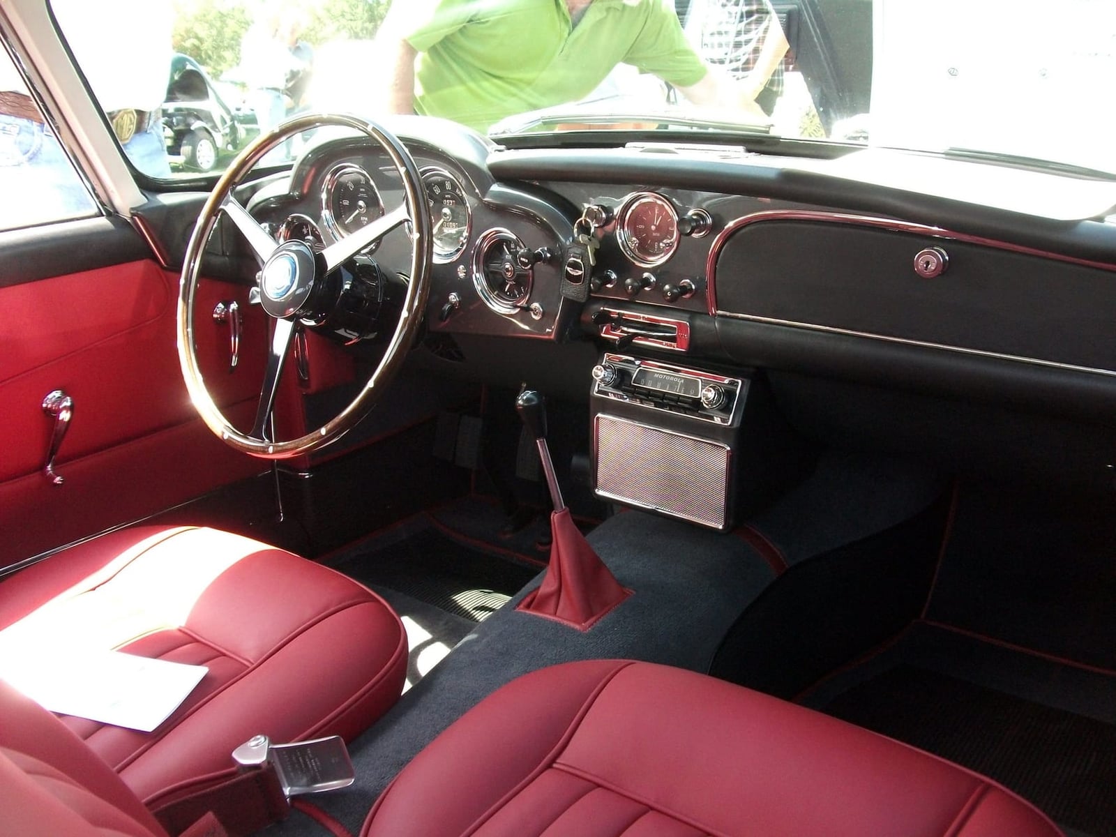 The red leather interior and wood-rimmed wheel of a 1961 Aston Martin DB4