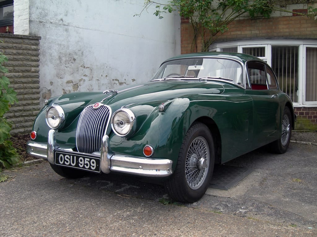 A British Racing Green 1961 Jaguar XK150 fixed head coupe, front three-quarter view, UK registration OSU 959