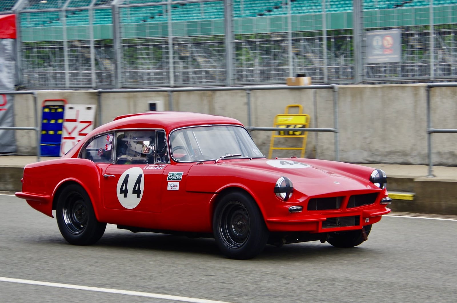 A red 1962 Reliant Sabre Six racing on a circuit with the number 44