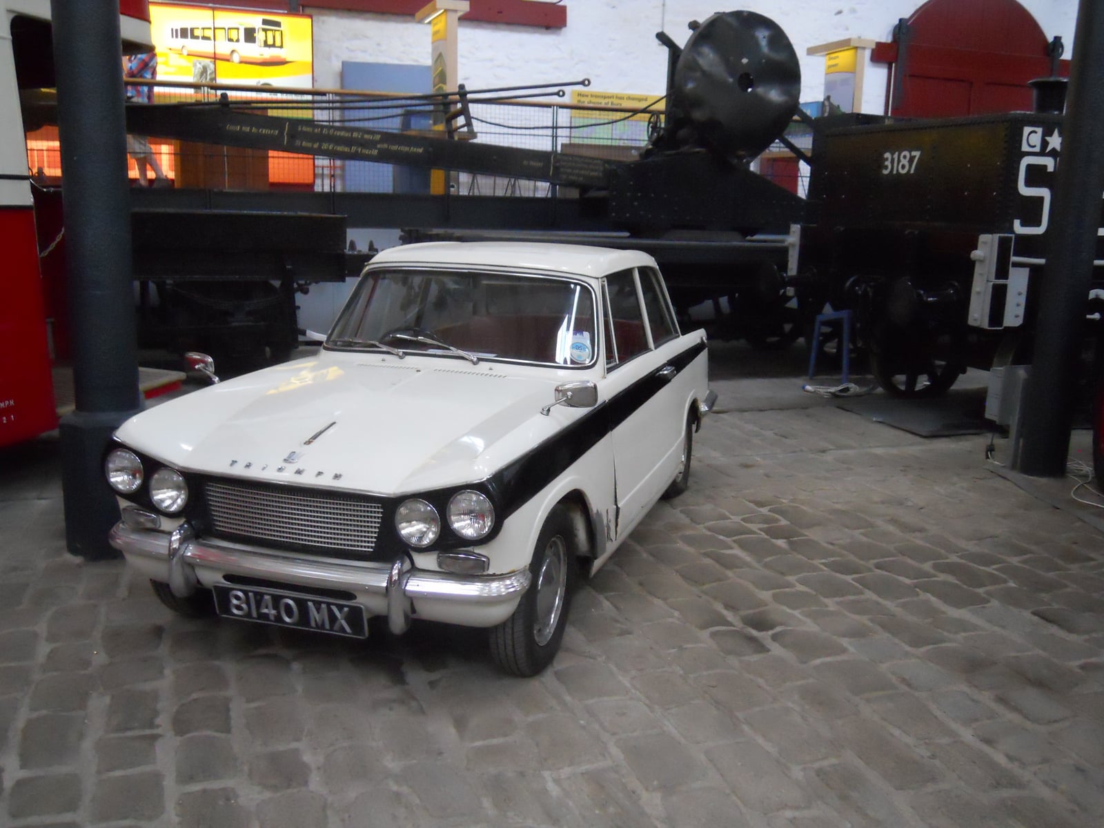 An early two-tone Triumph Herald saloon on display in a transport museum