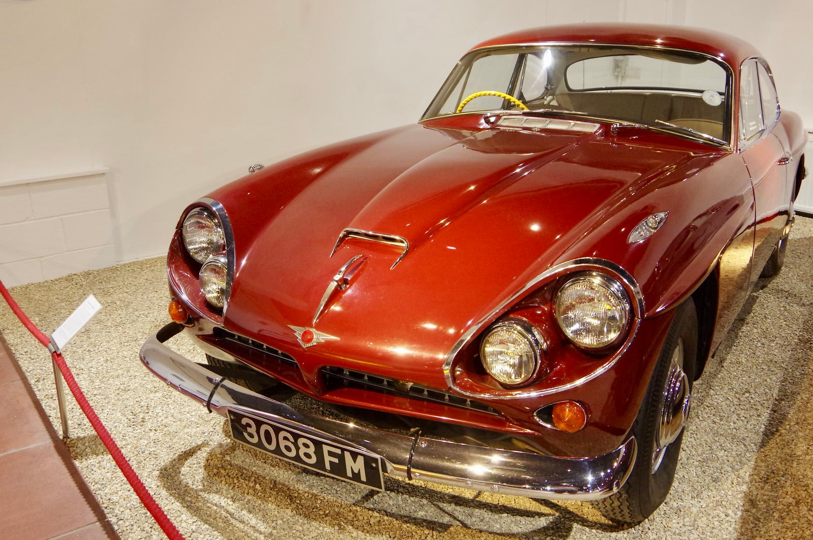 A red Jensen CV8 Mark 1 at an indoor display, front three-quarter view