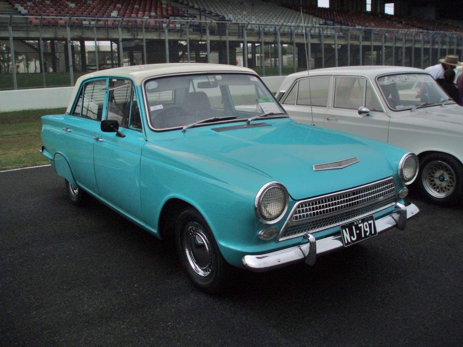 A turquoise and white two-tone Ford Consul Cortina at a classic car gathering, front three-quarter view