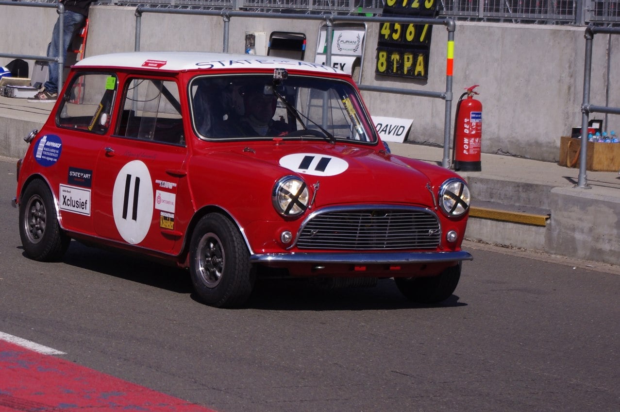A red Mini Cooper S race car at a historic meeting