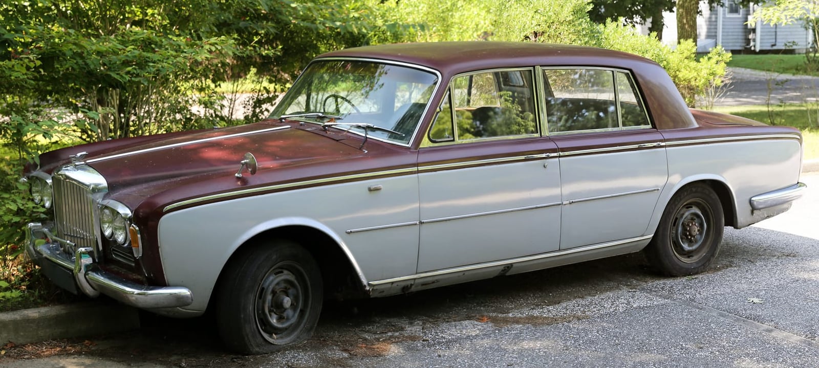 A weathered early Bentley T-series with faded paint and a vinyl roof