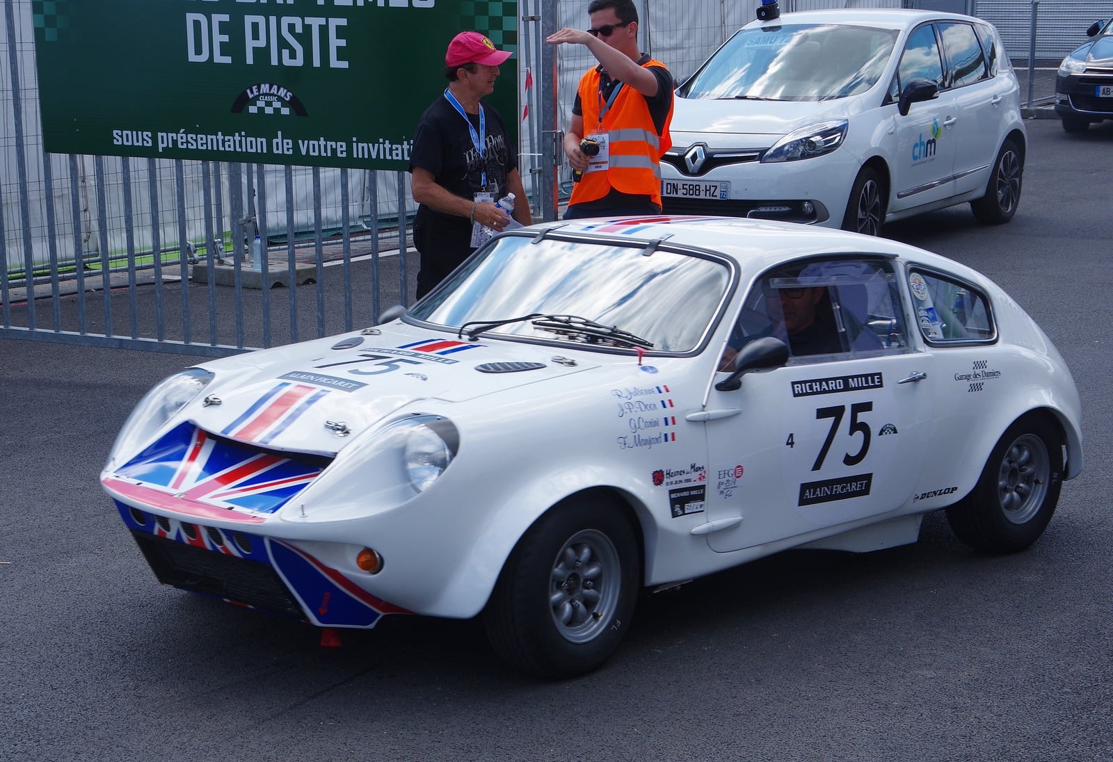 A white Mini Marcos in period racing trim with a competition number and a Union Jack on the nose