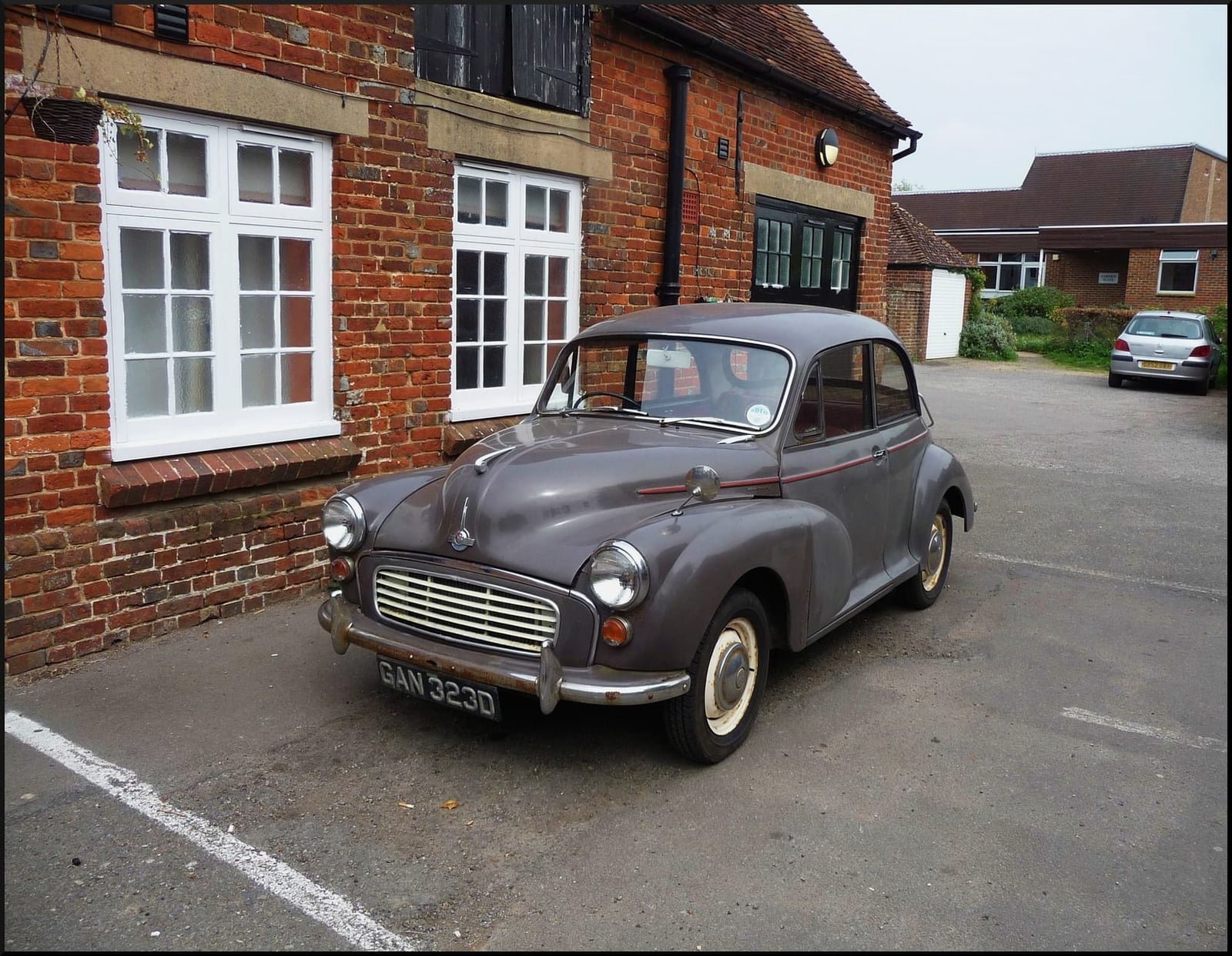 A grey 1966 Morris Minor 1000 parked outside a brick building, front three-quarter view, UK registration GAN 323D