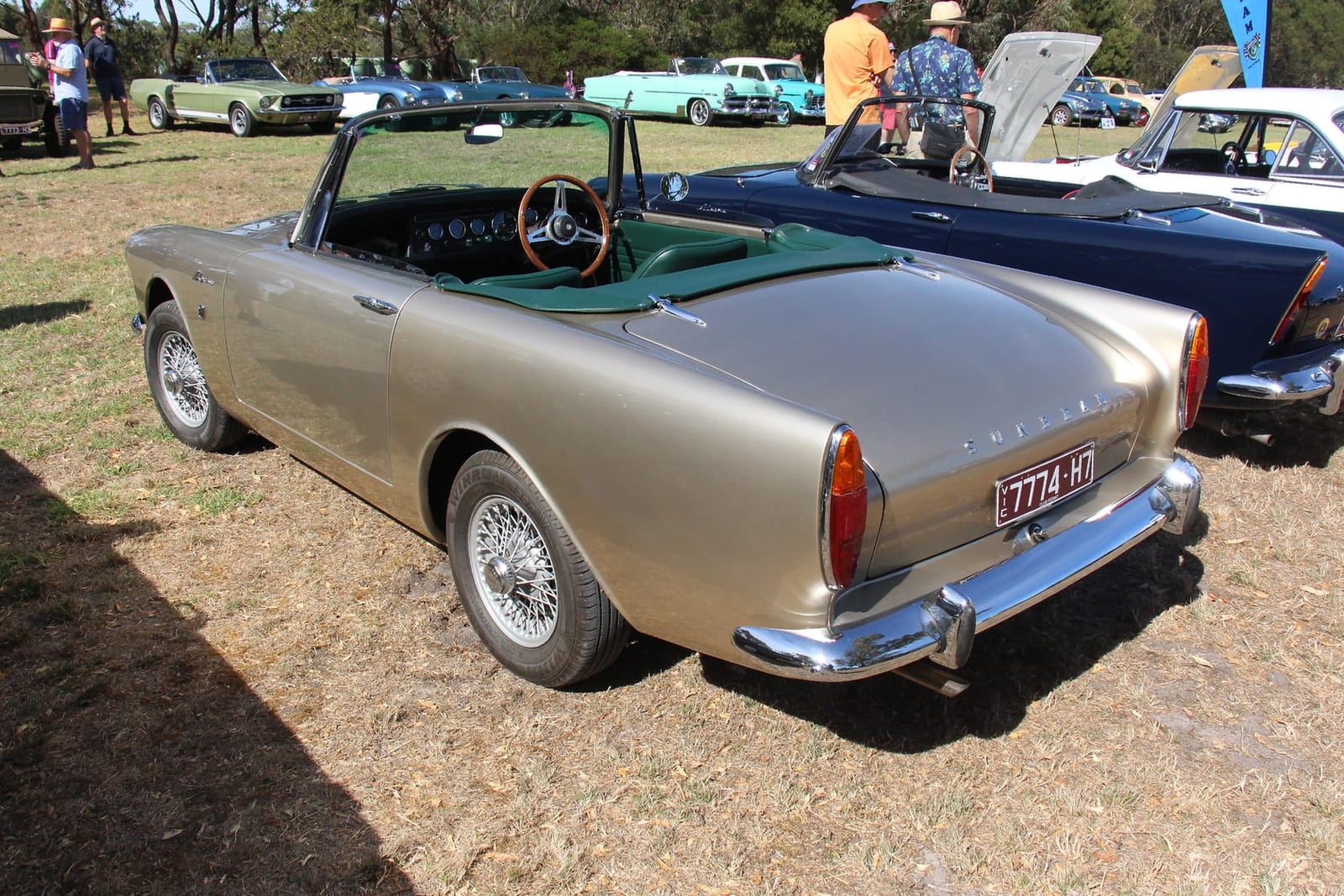 The rear three-quarter of a champagne-coloured 1966 Sunbeam Alpine Series V on a showfield
