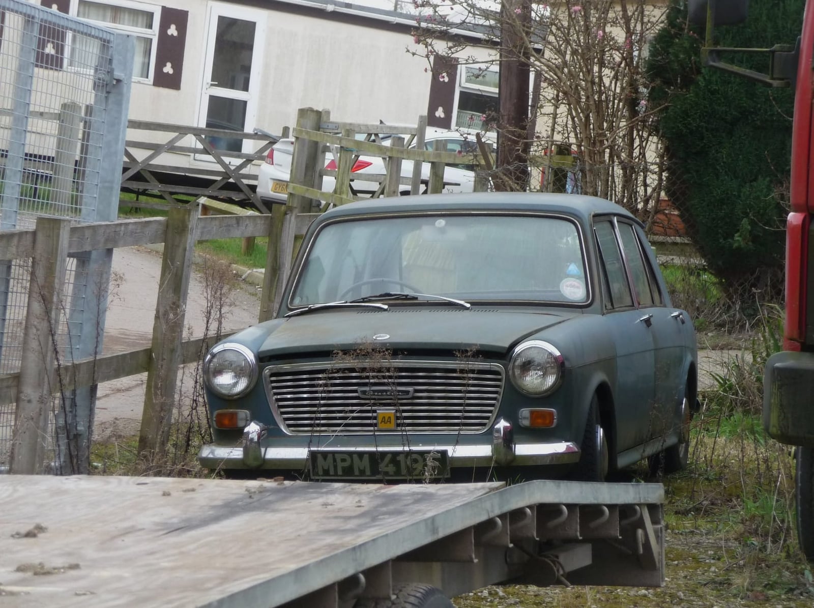 A grey 1967 Austin 1100 parked beside a fence, front three-quarter view, UK registration NPH 419E