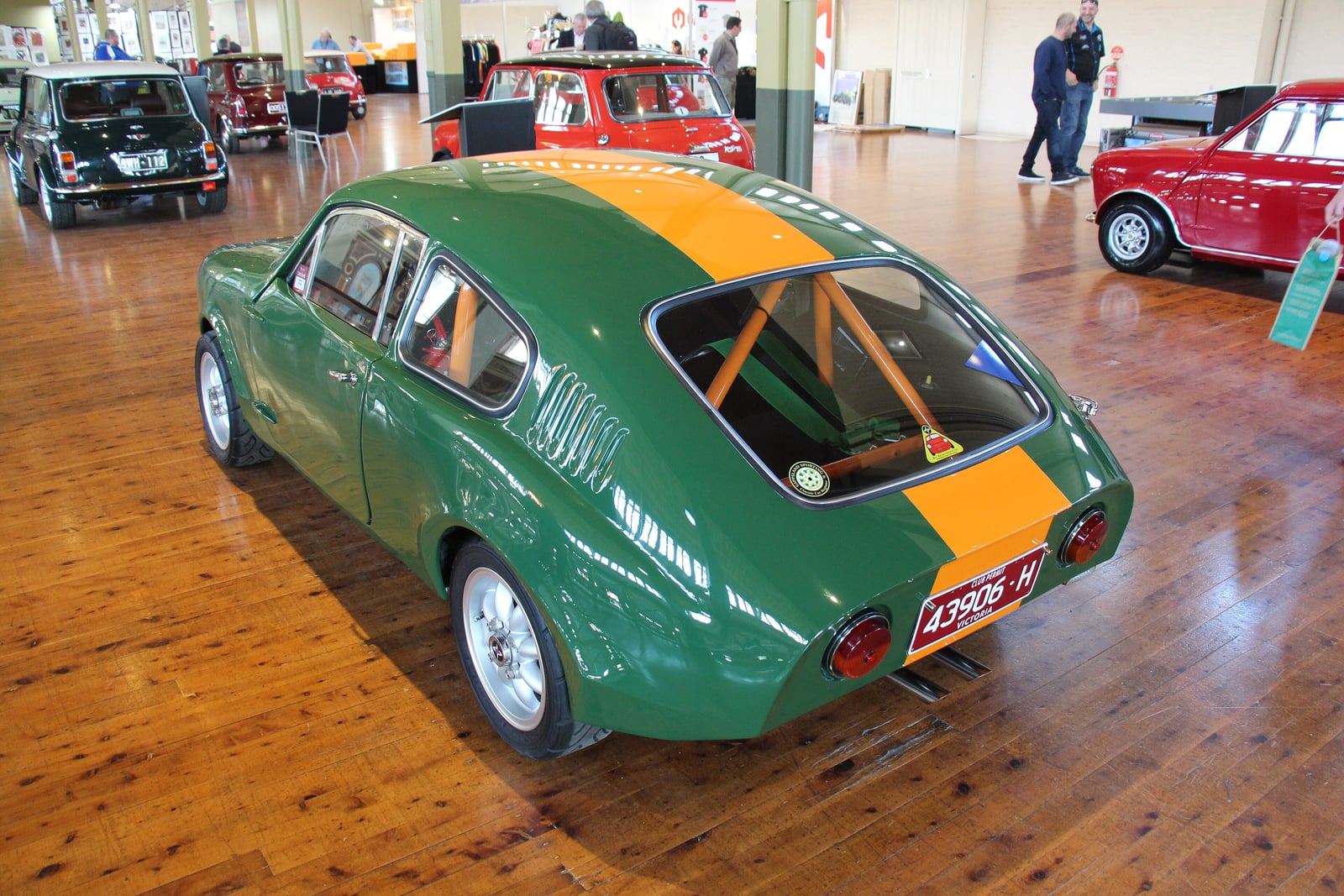 A green 1967 Mini Marcos Mk III GT coupe at a wet classic car show