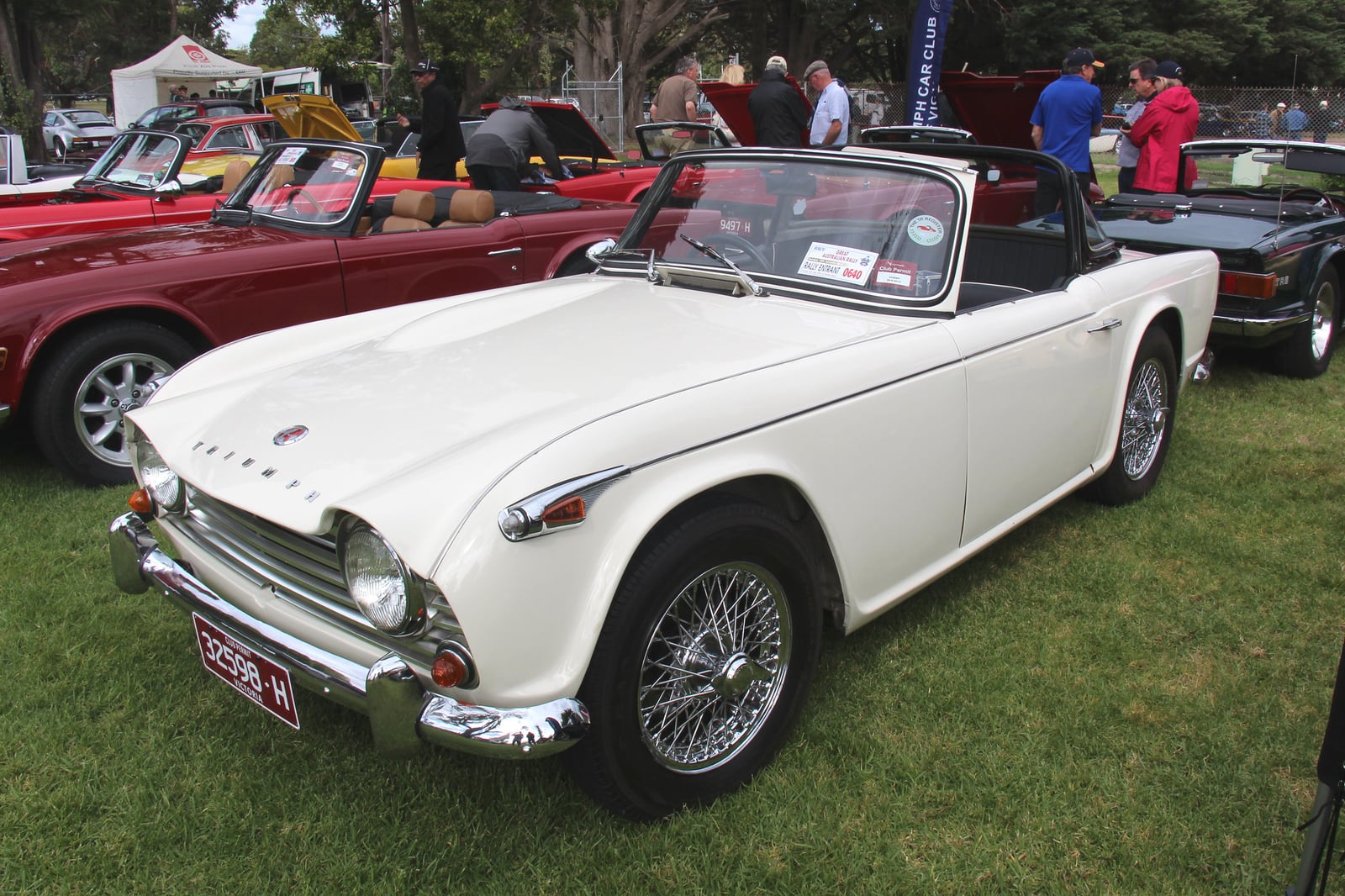 A white Triumph TR4A roadster with the top down, front three-quarter view at a show
