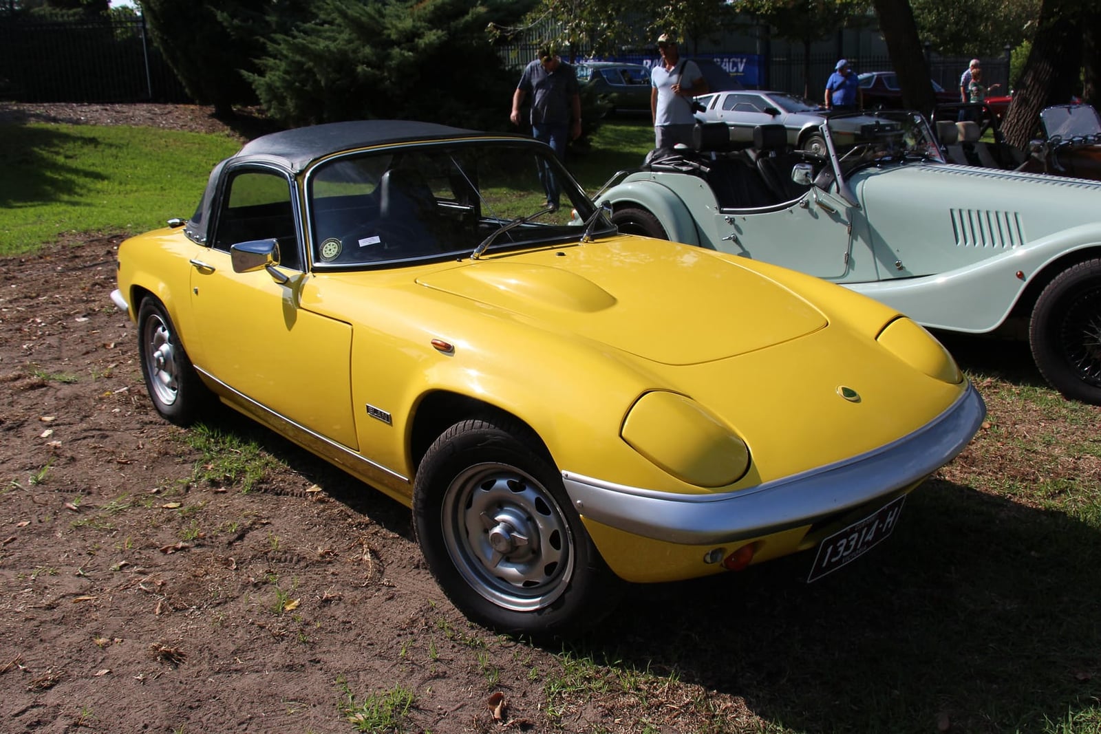 A yellow 1968 Lotus Elan Series 4 with black hardtop on grass, front three-quarter view