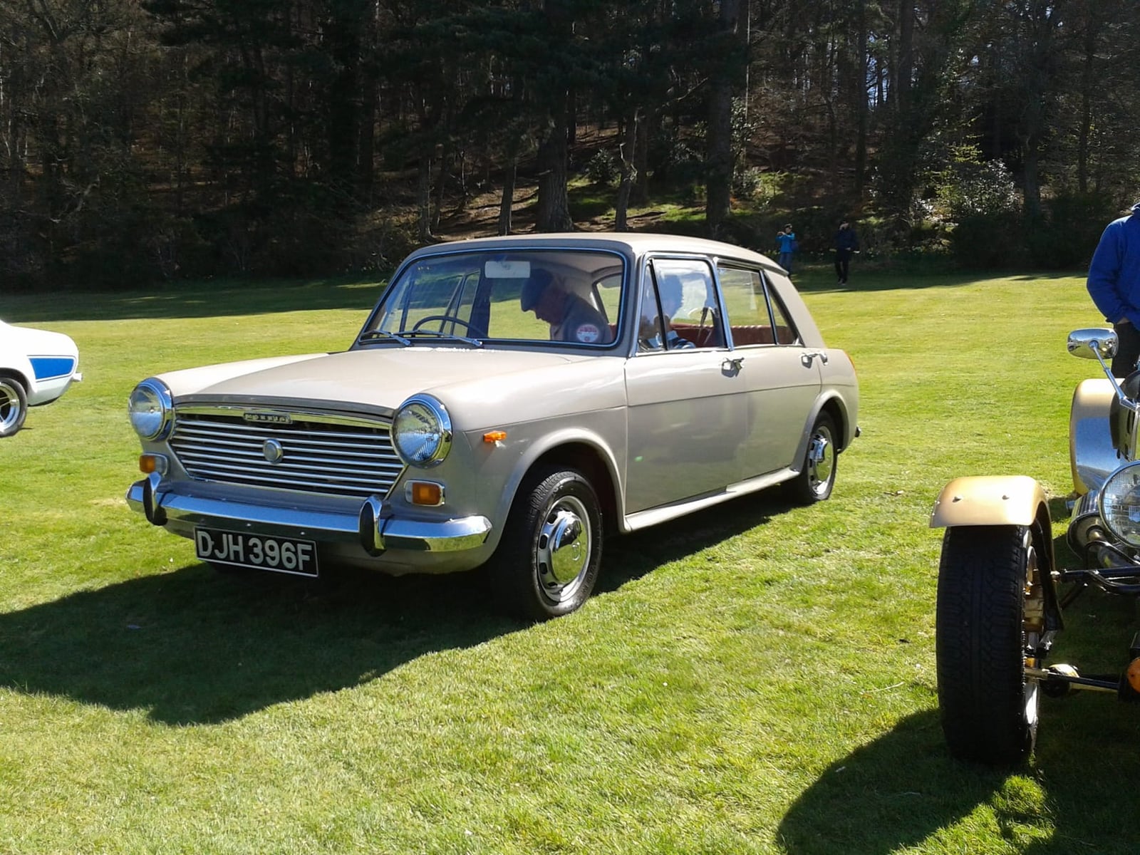A silver 1968 Morris 1100 on grass at a classic car show, front three-quarter view