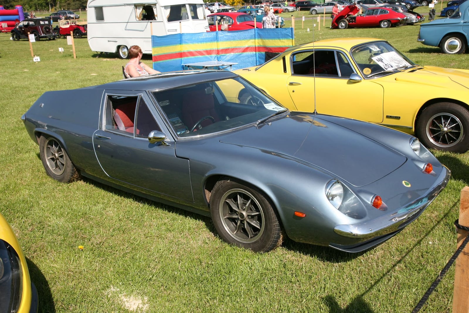 A grey-blue 1969 Lotus Europa S2 on grass at a classic car show, side view