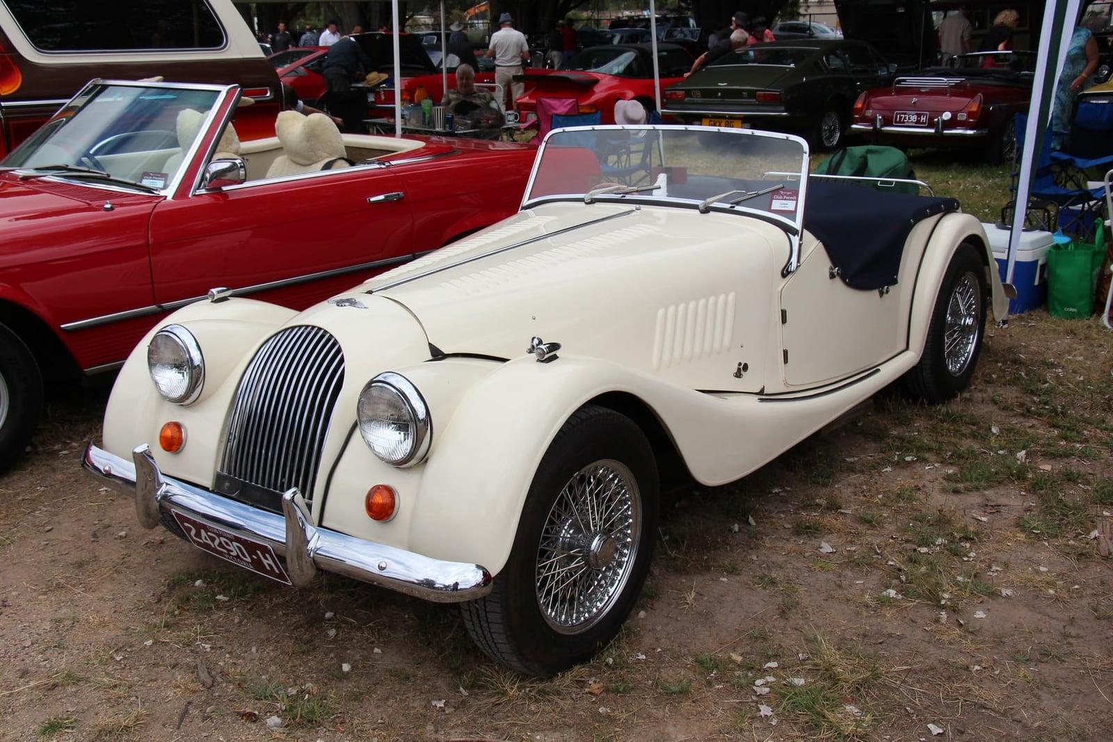 A cream 1969 Morgan 4/4 1600 roadster at an indoor classic car show, front three-quarter view