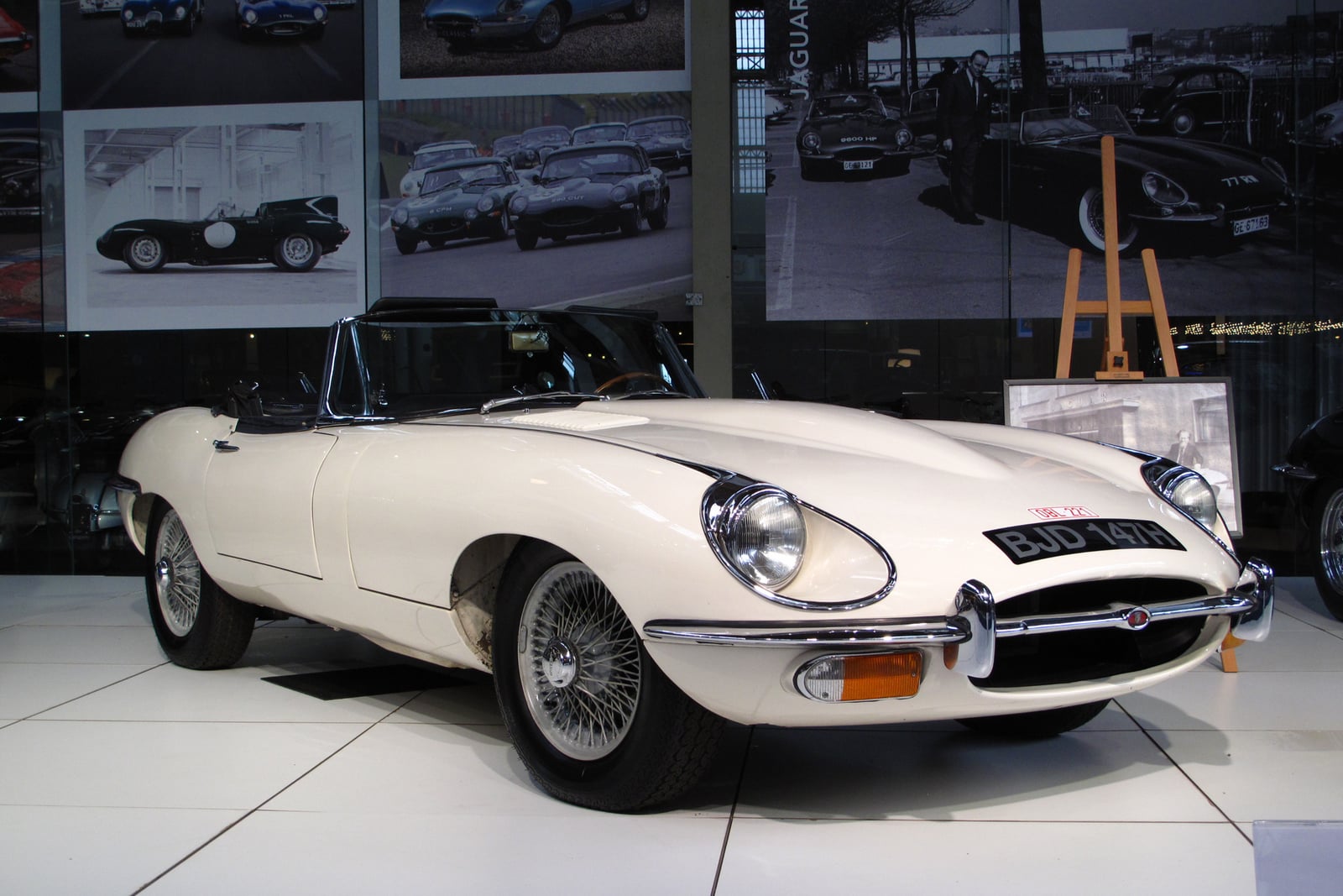A cream Jaguar E-Type Series 2 open roadster with open headlamps and chrome wire wheels, front three-quarter view