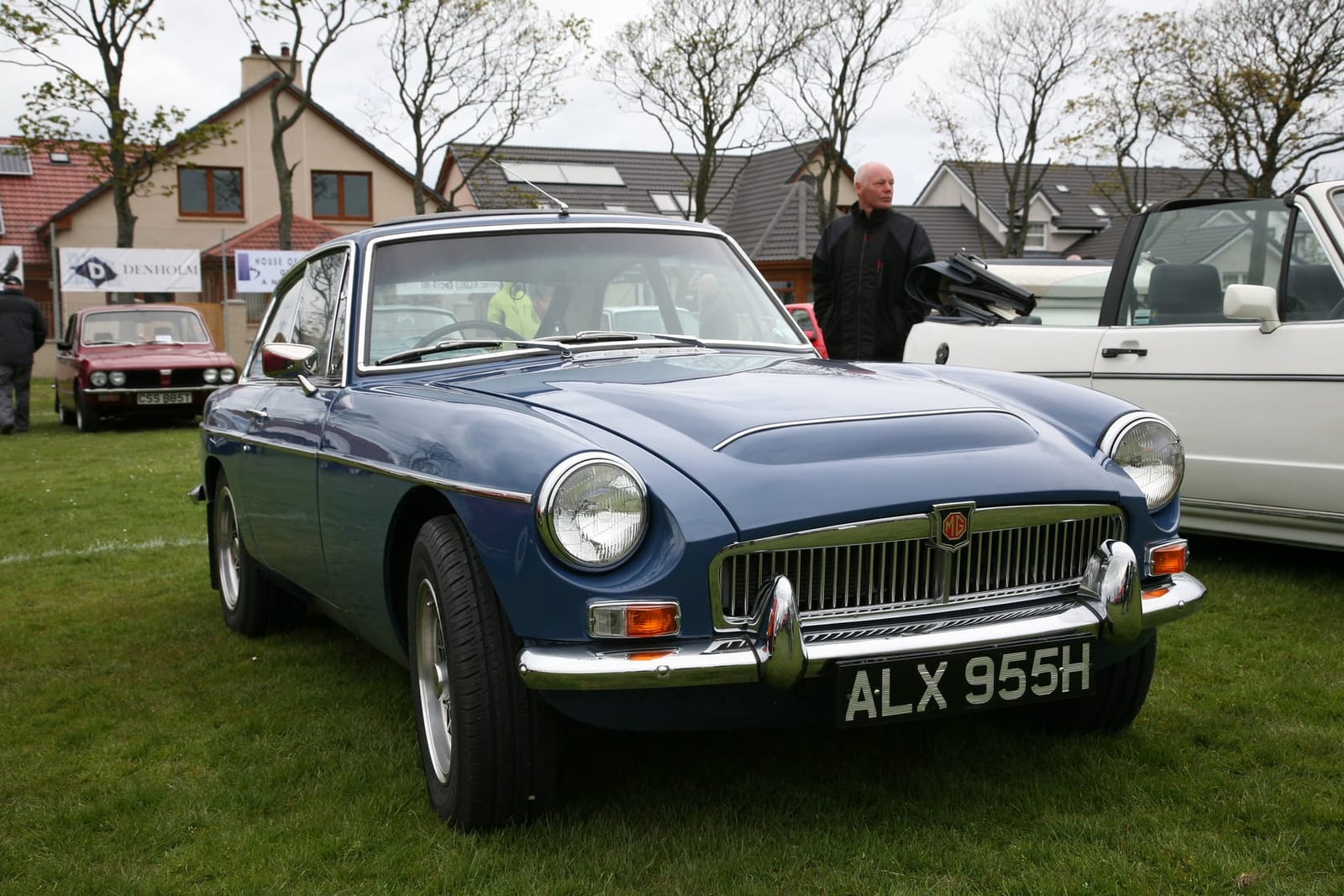 A blue 1970 MGC GT with a UK registration parked on grass at a show