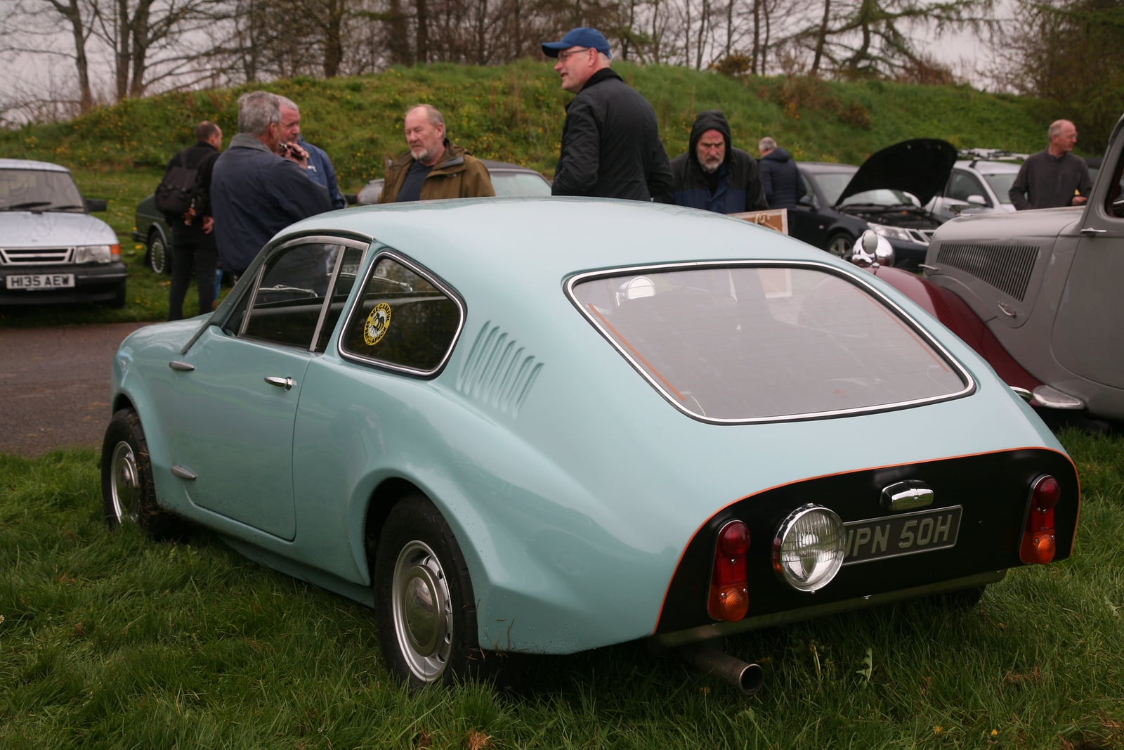 A pale green Mini Marcos coupe seen from the rear three-quarter, showing the cut-off tail, at a classic car show