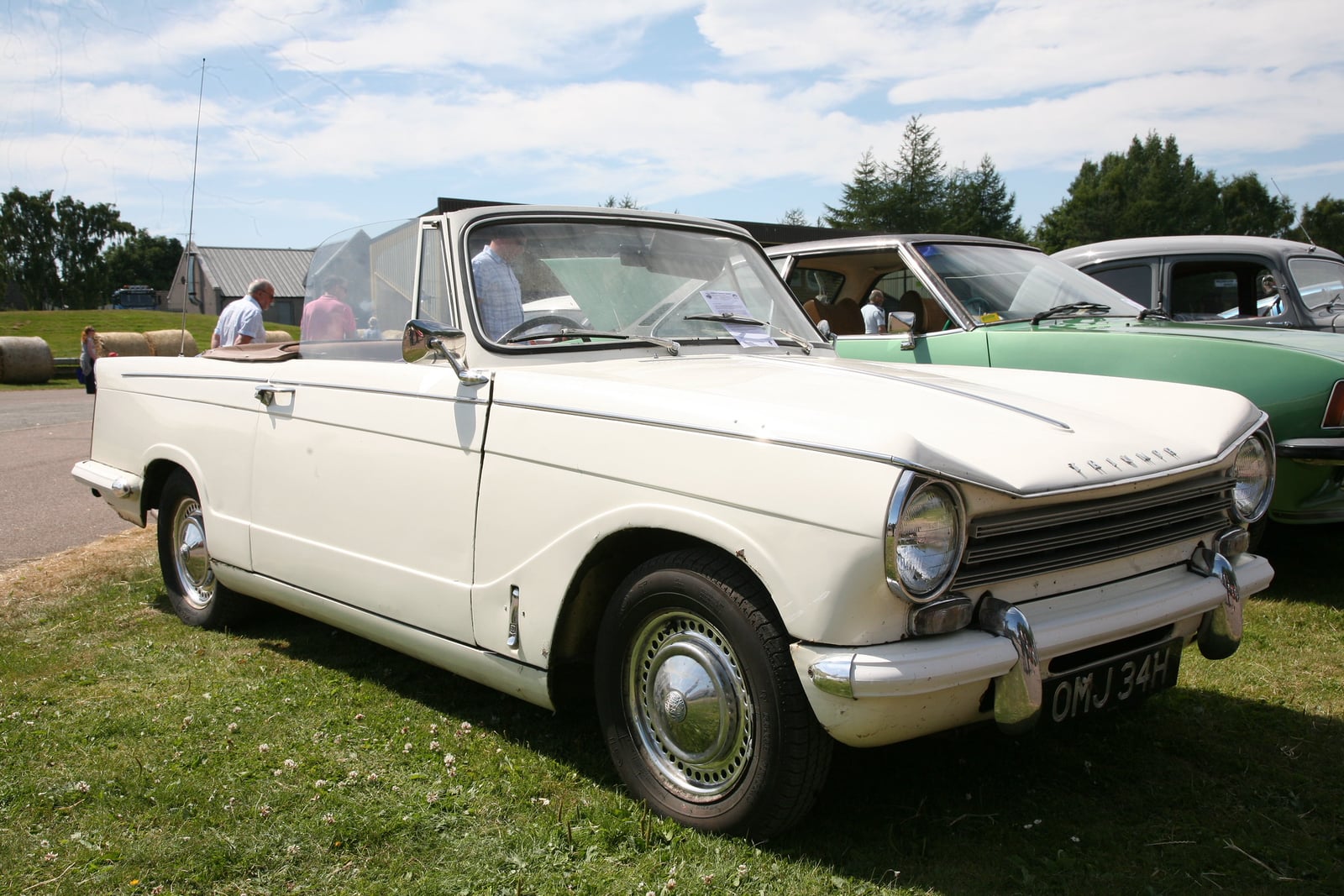 A cream Triumph Herald convertible with the top down, front three-quarter view on grass