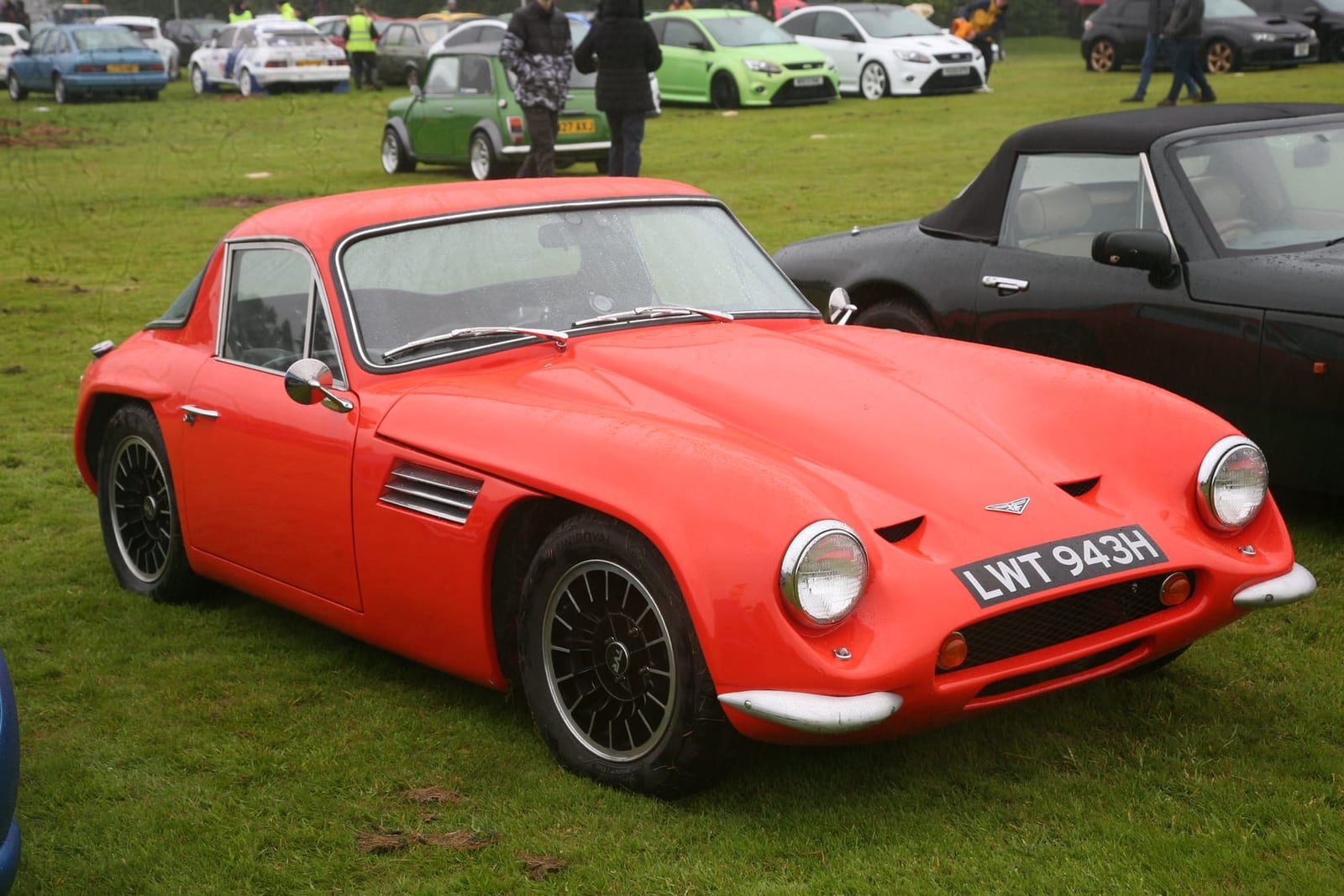 A red-orange 1970 TVR Vixen S3 with UK registration LWT 943H on a show field