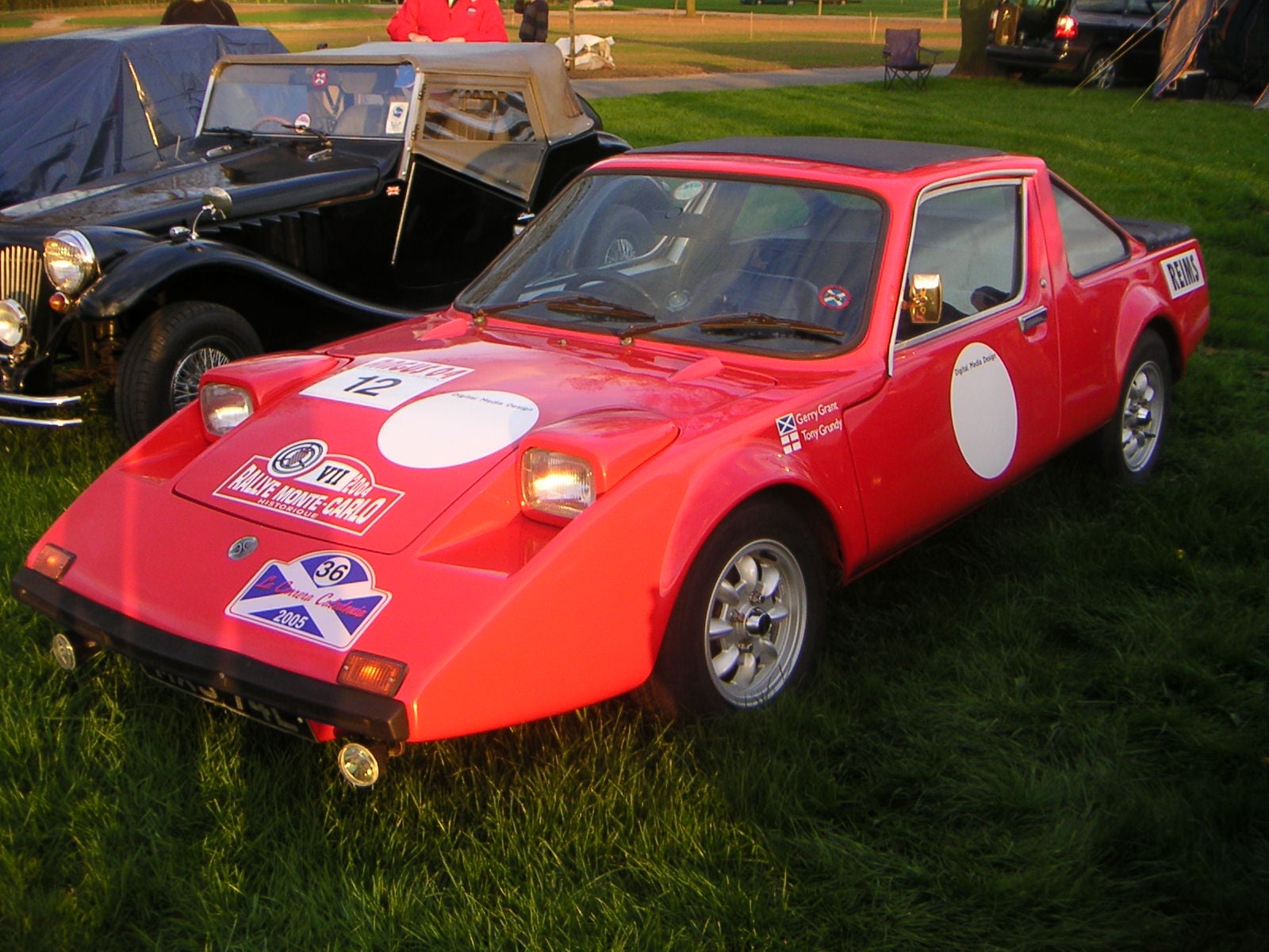 A red Clan Crusader with a competition roundel and a Scottish saltire sticker, front three-quarter view at a classic car show