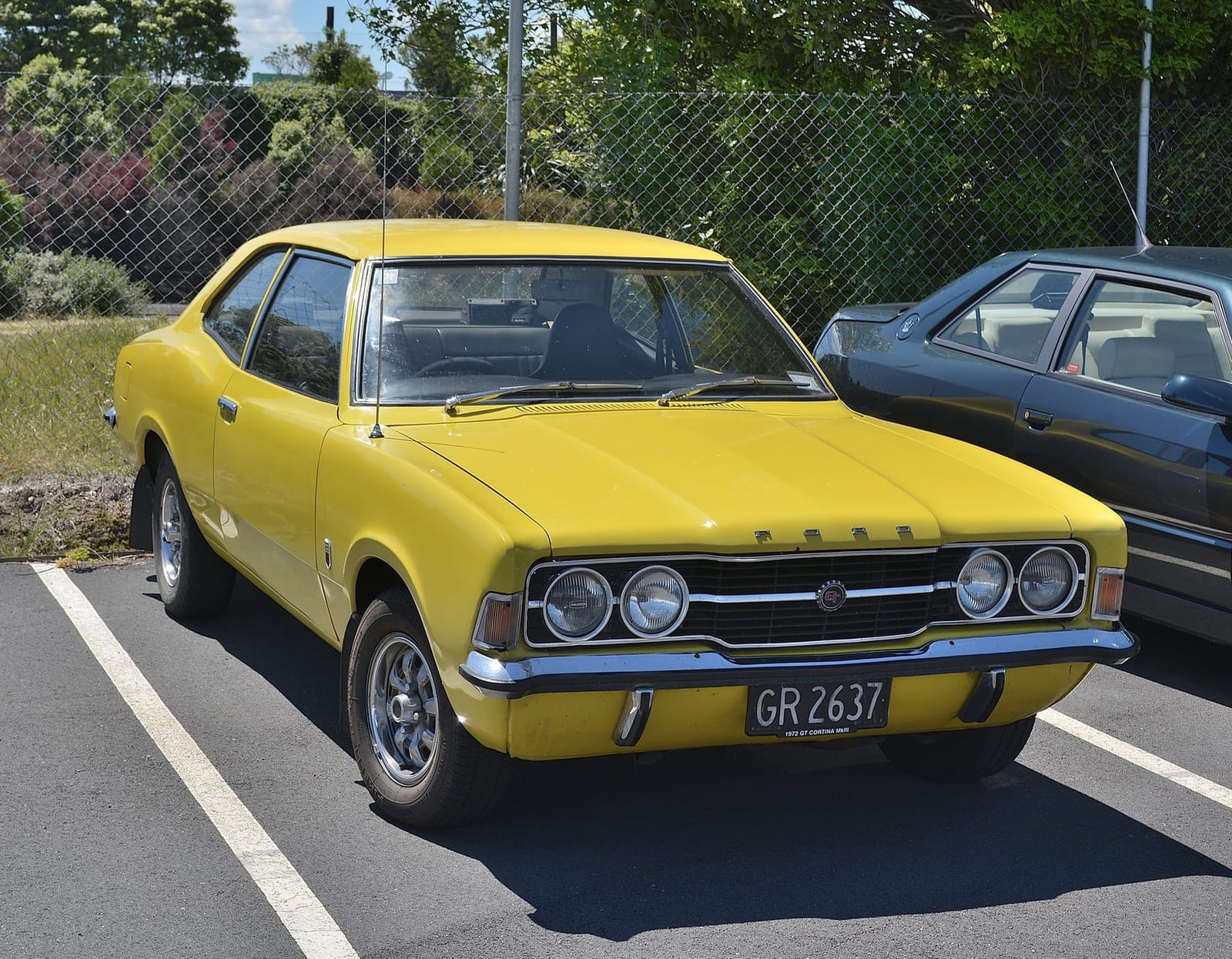 A yellow 1972 Ford Cortina Mk3 two-door with a UK registration in a car park