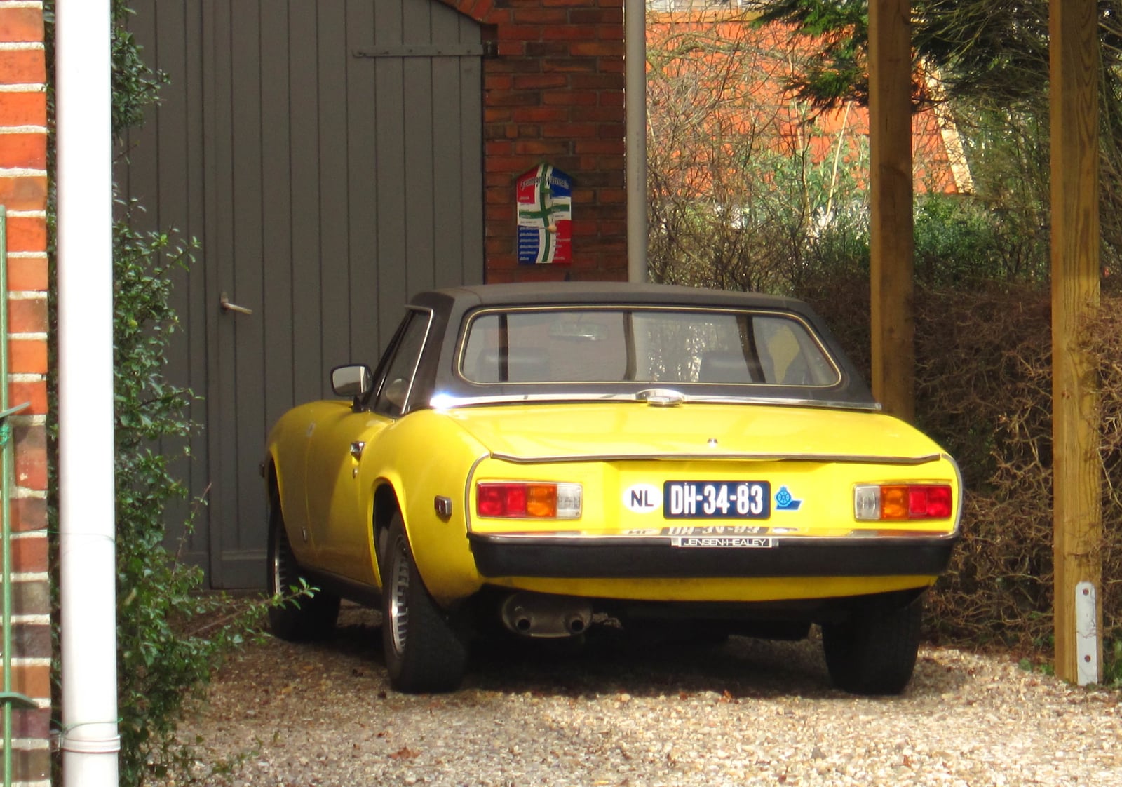 A yellow Jensen-Healey roadster seen from the rear three-quarter on grass