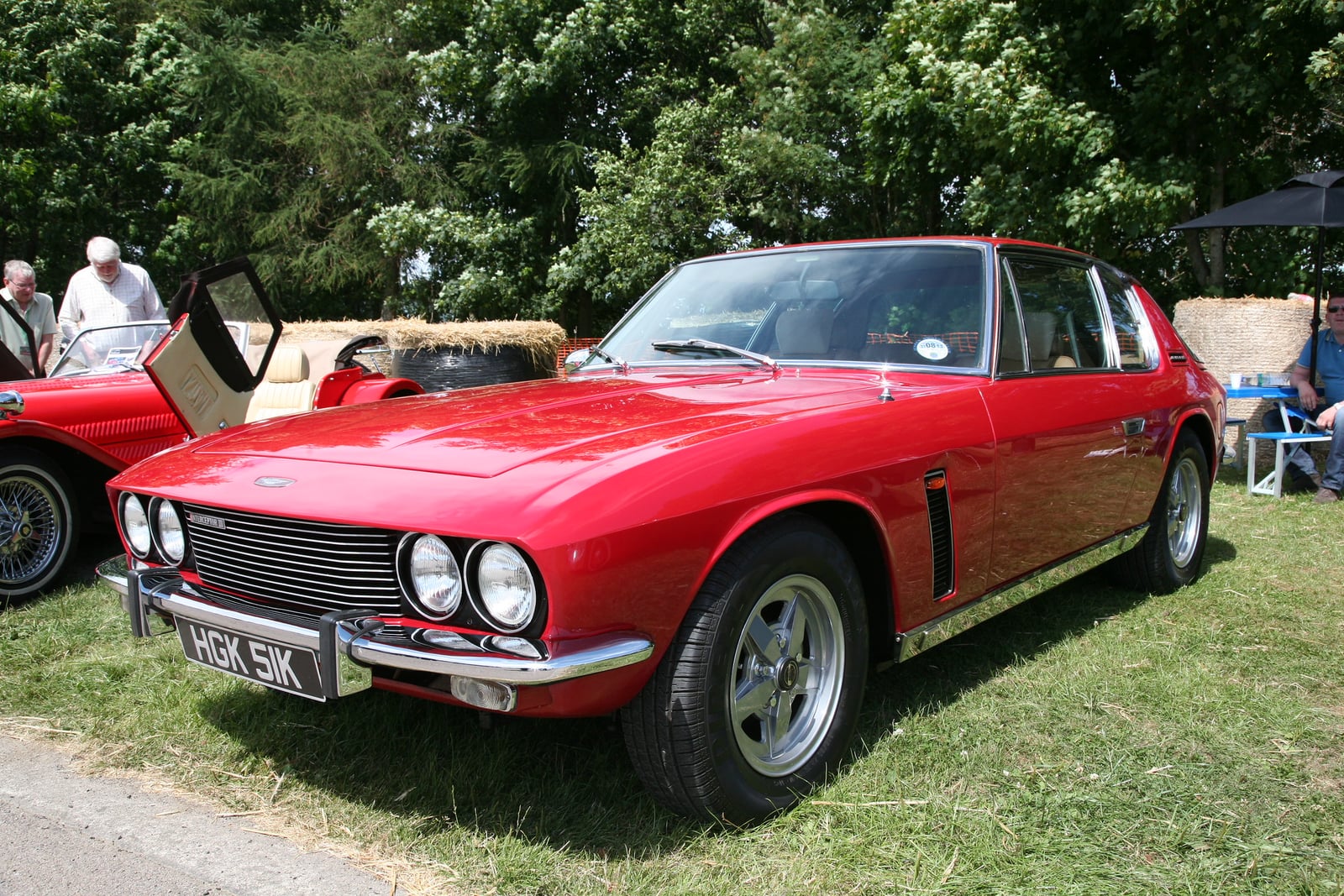A red Jensen Interceptor parked on grass, front three-quarter view