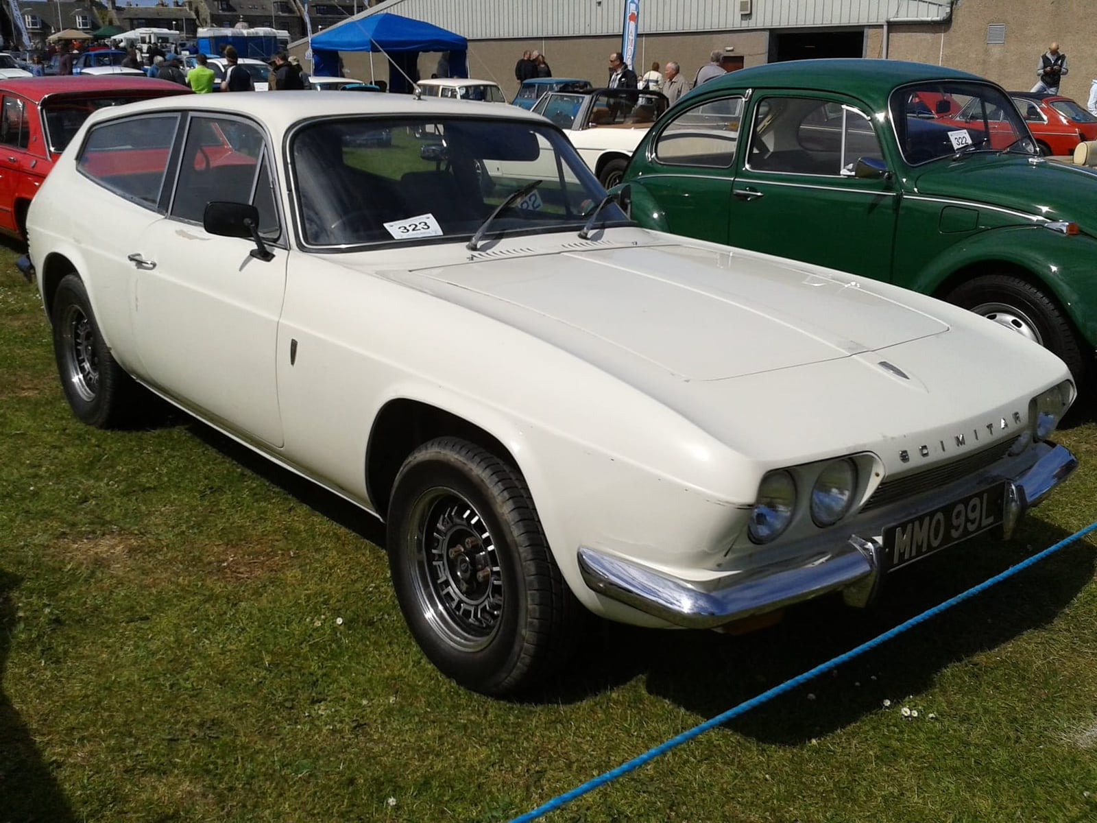 A white 1972 Reliant Scimitar GTE on grass at a show, front three-quarter view, UK registration MMO 99L