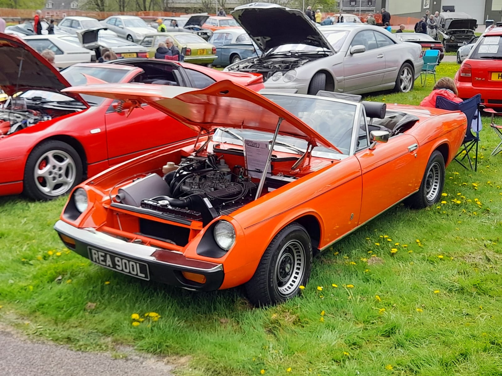 An orange Jensen-Healey roadster with the top down, side view