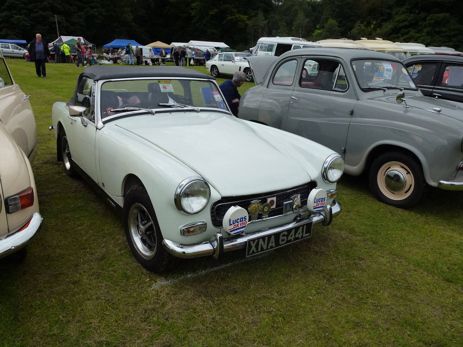 A pale green MG Midget with chrome bumpers and round wheel arches, front three-quarter view at a show