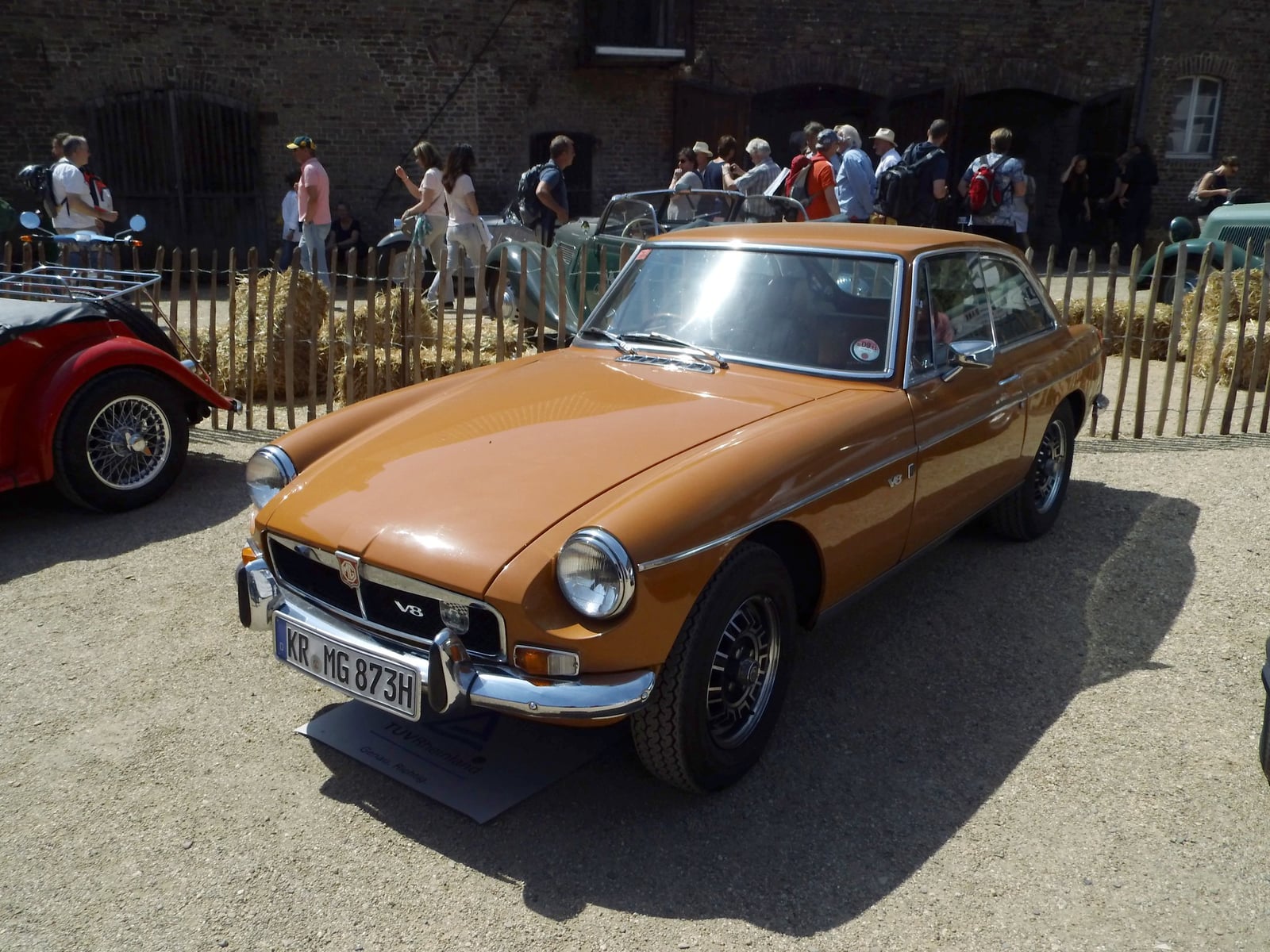 A bronze MG MGB GT V8 with its V8 badge, front three-quarter view at a show