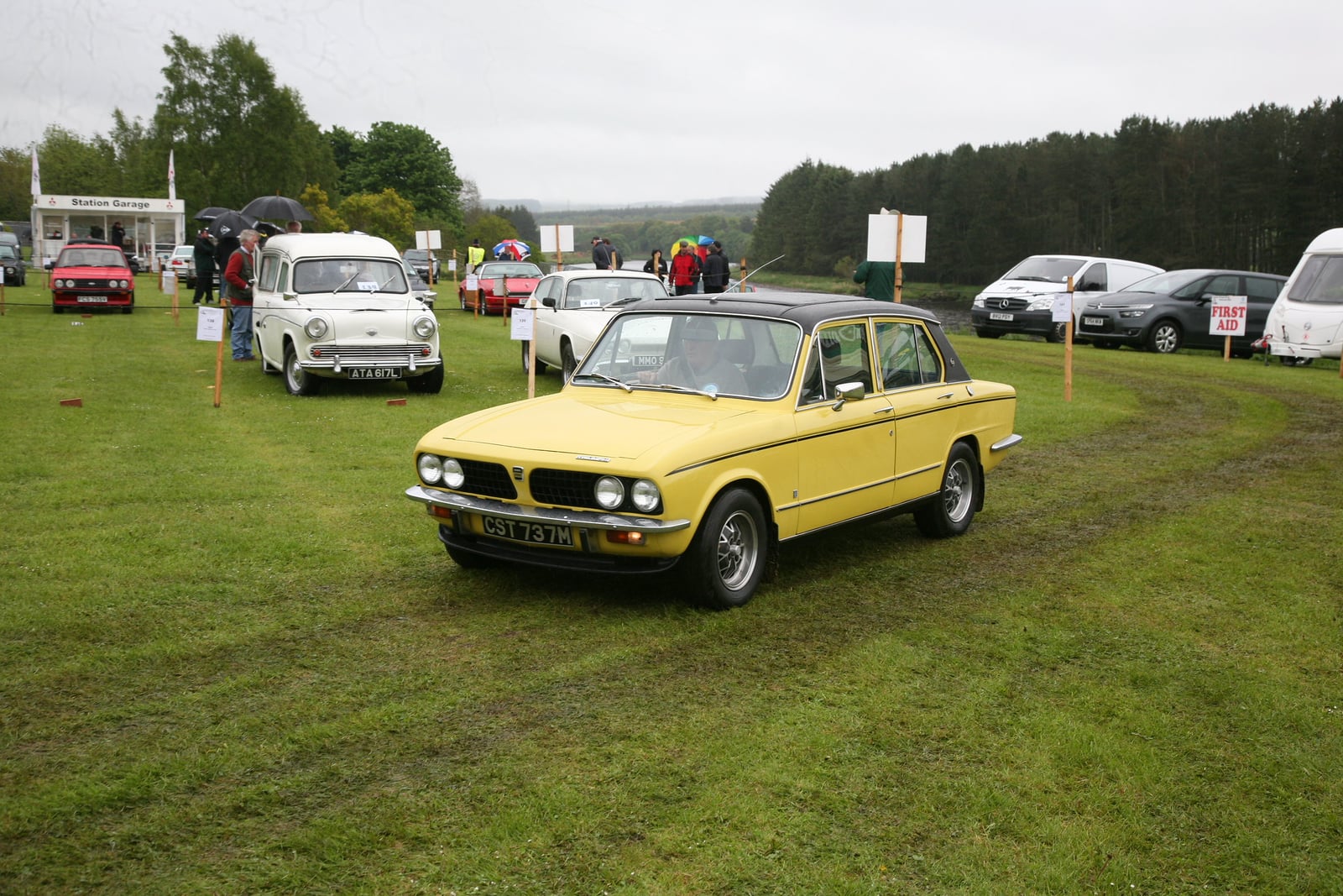 A yellow Triumph Dolomite Sprint with a black vinyl roof, front three-quarter view at a show
