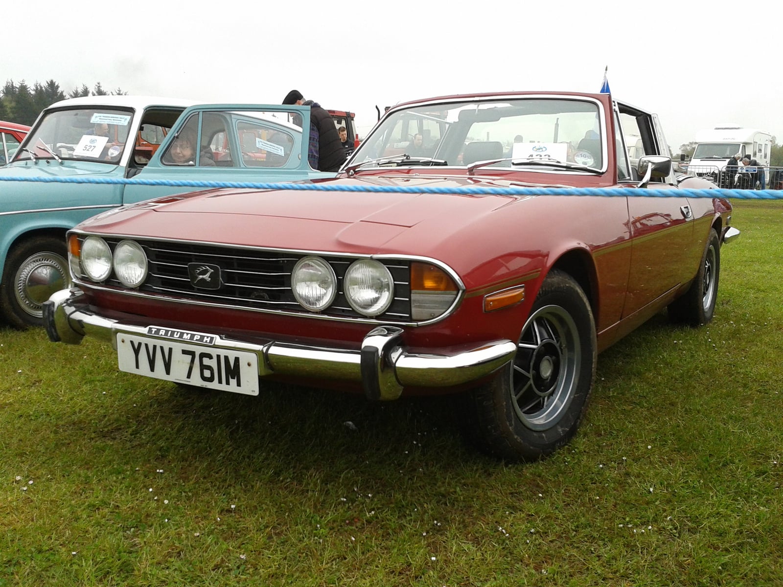 A tan Triumph Stag with its removable hardtop fitted, front three-quarter view among autumn trees