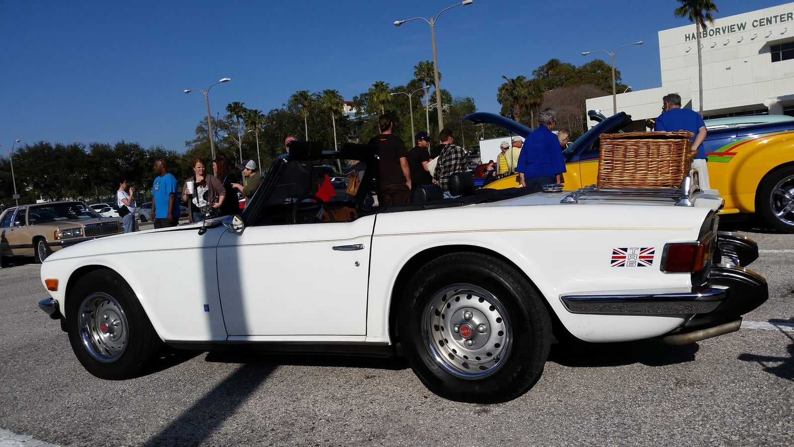 A white 1975 Triumph TR6 in United States specification with its hood down at an American car show