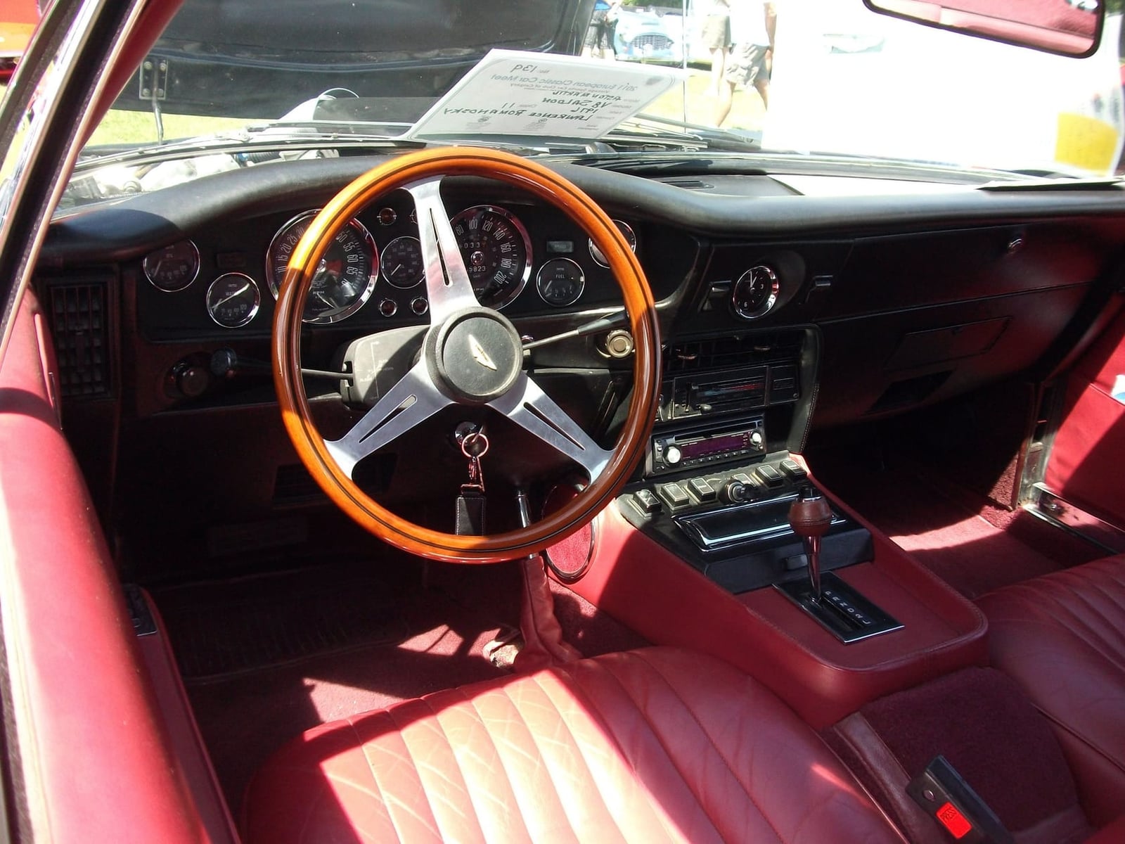 The red leather interior and wood-rimmed steering wheel of a 1976 Aston Martin V8