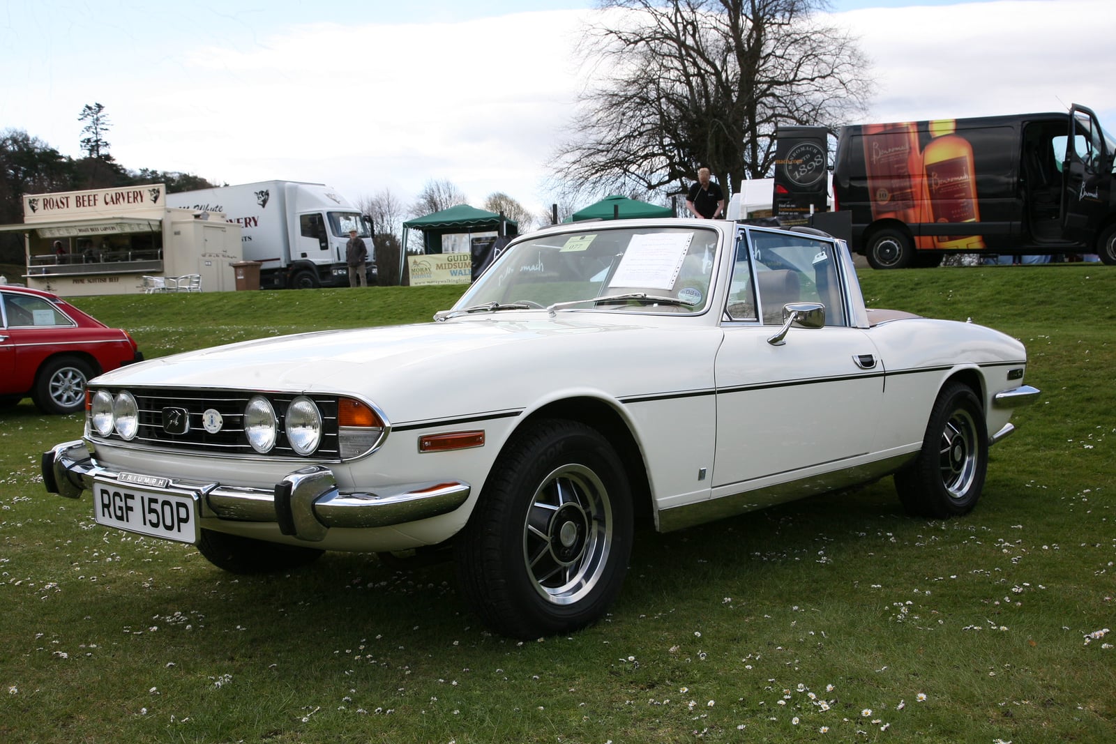 A white Triumph Stag with the top down, front three-quarter view at a show