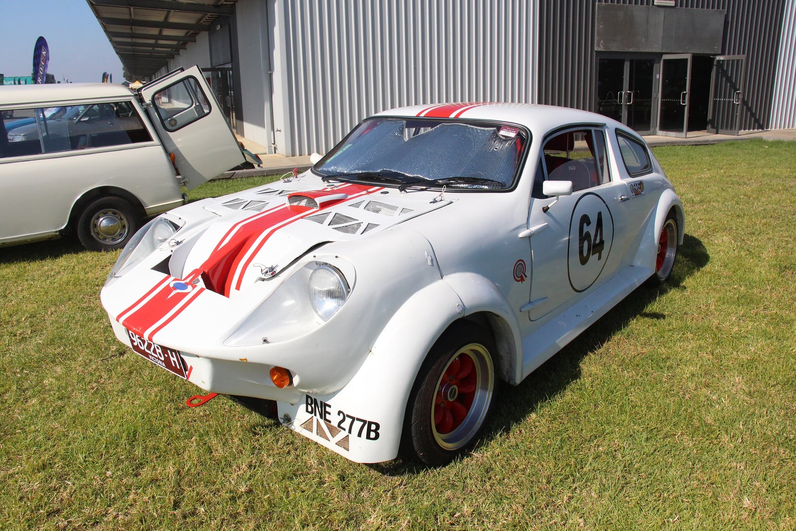 A white and red 1977 Mini Marcos Mk IV coupe, front three-quarter view