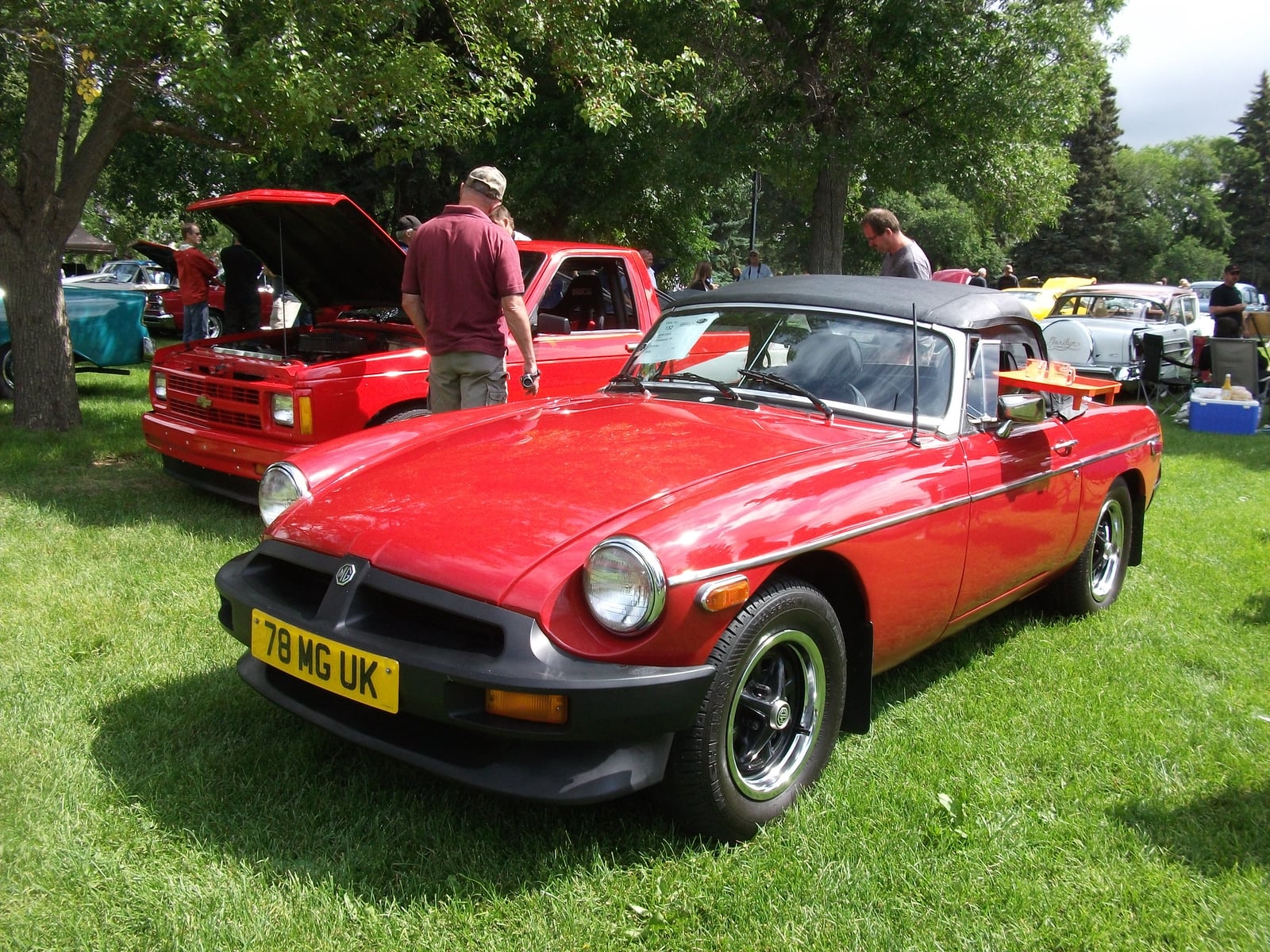 A red rubber-bumper MG MGB roadster, front three-quarter view on grass at a show