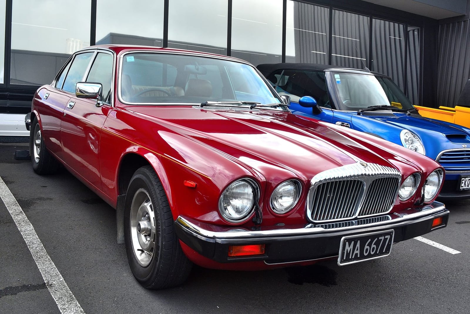 A red 1980 Daimler Sovereign at a classic car show, front three-quarter view, UK registration MA 6677