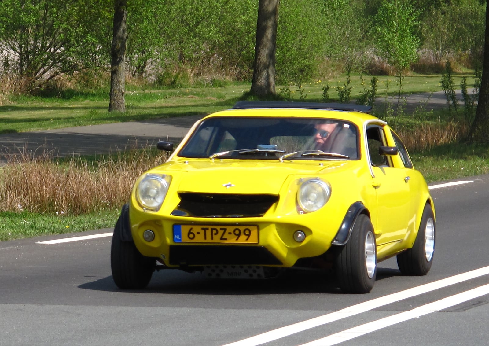 A yellow 1980 Mini Marcos 1300 coupe on a road, front three-quarter view