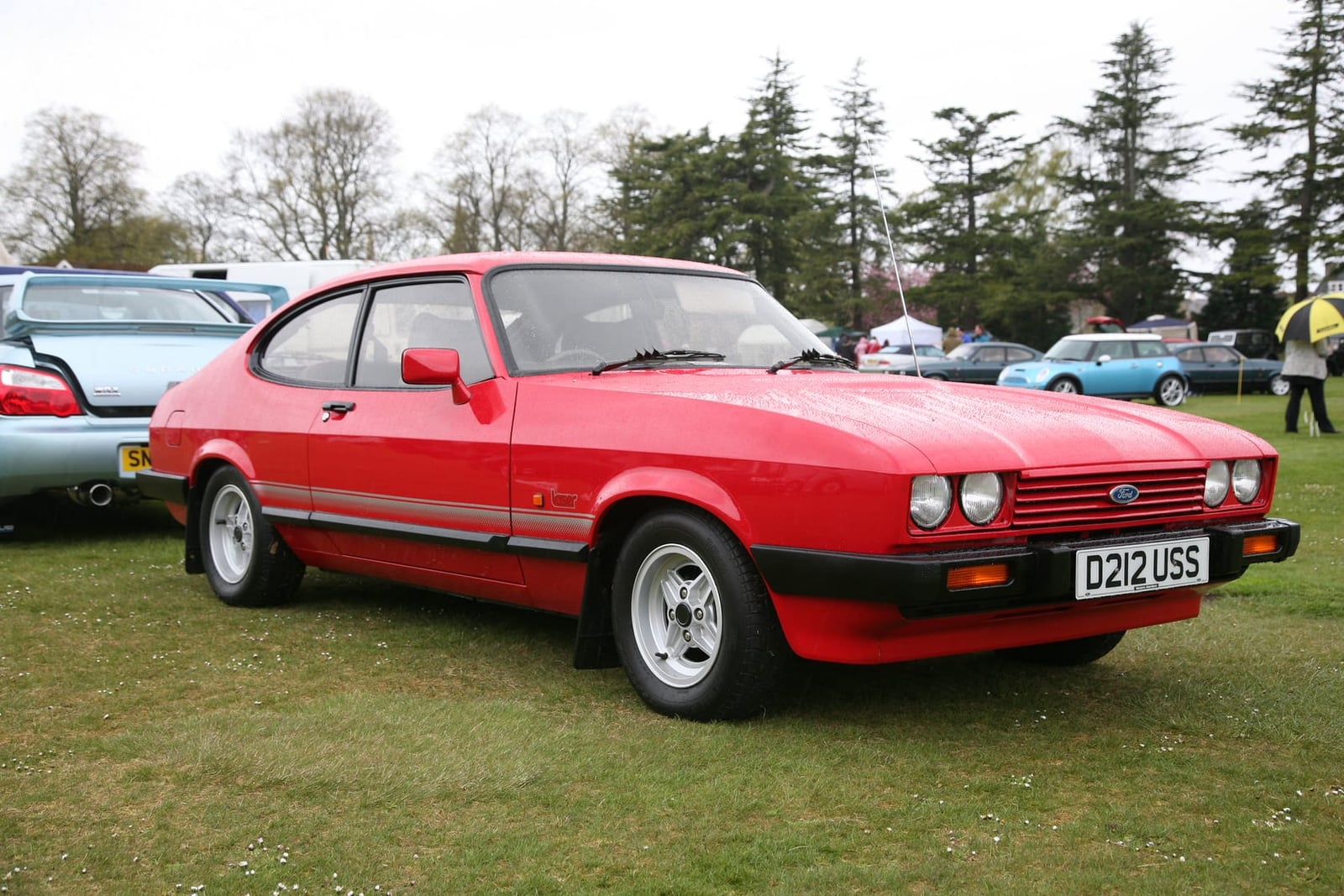A red 1986 Ford Capri Laser 1.6 with a UK registration on a show field