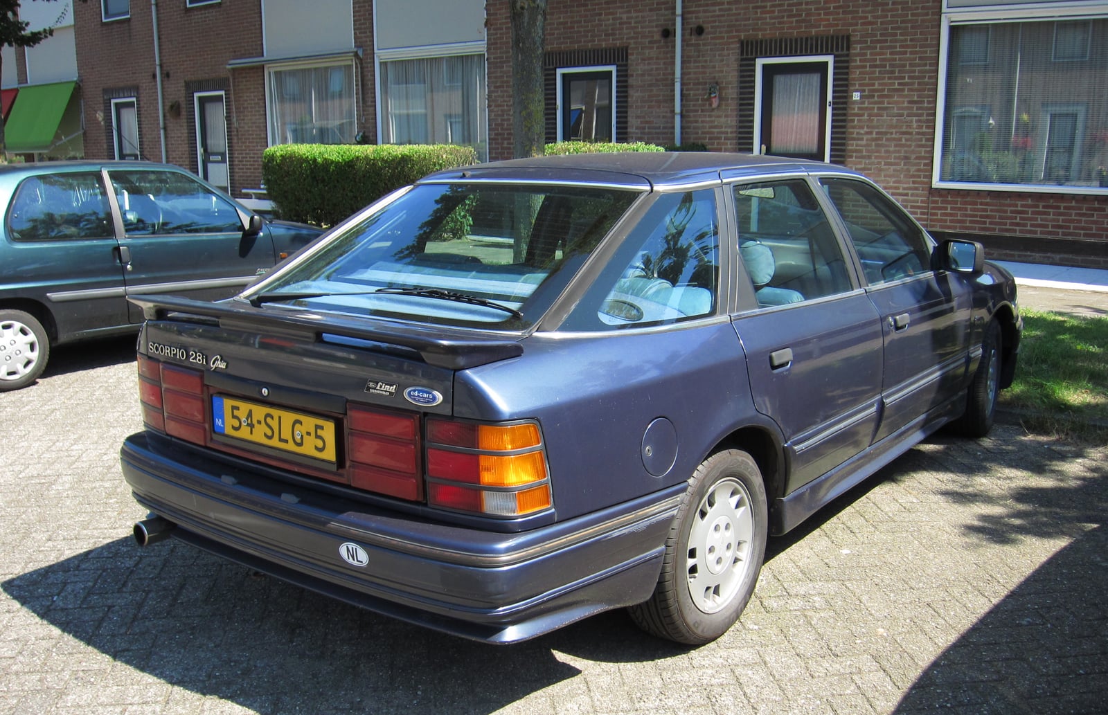 A grey Ford Scorpio 2.8i Ghia, rear three-quarter view on a street, the hatchback tailgate and Scorpio badge visible