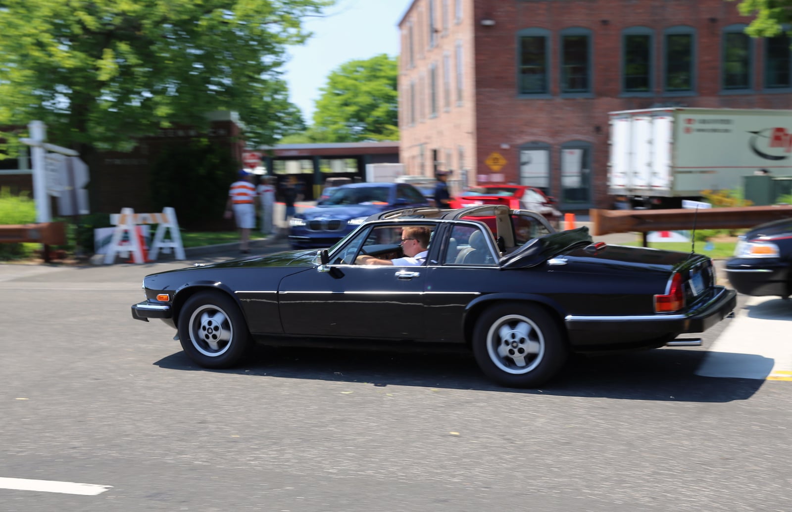 A black Jaguar XJ-SC cabriolet with the roof open, side view