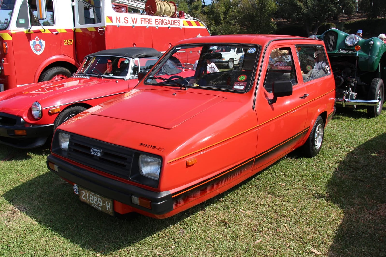A red 1986 Reliant Rialto SE estate on grass at a classic vehicle show, front three-quarter view