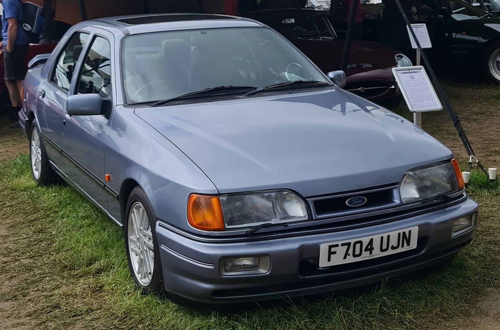 A pale blue Ford Sierra Sapphire RS Cosworth four-door with a UK registration on grass at a classic car event