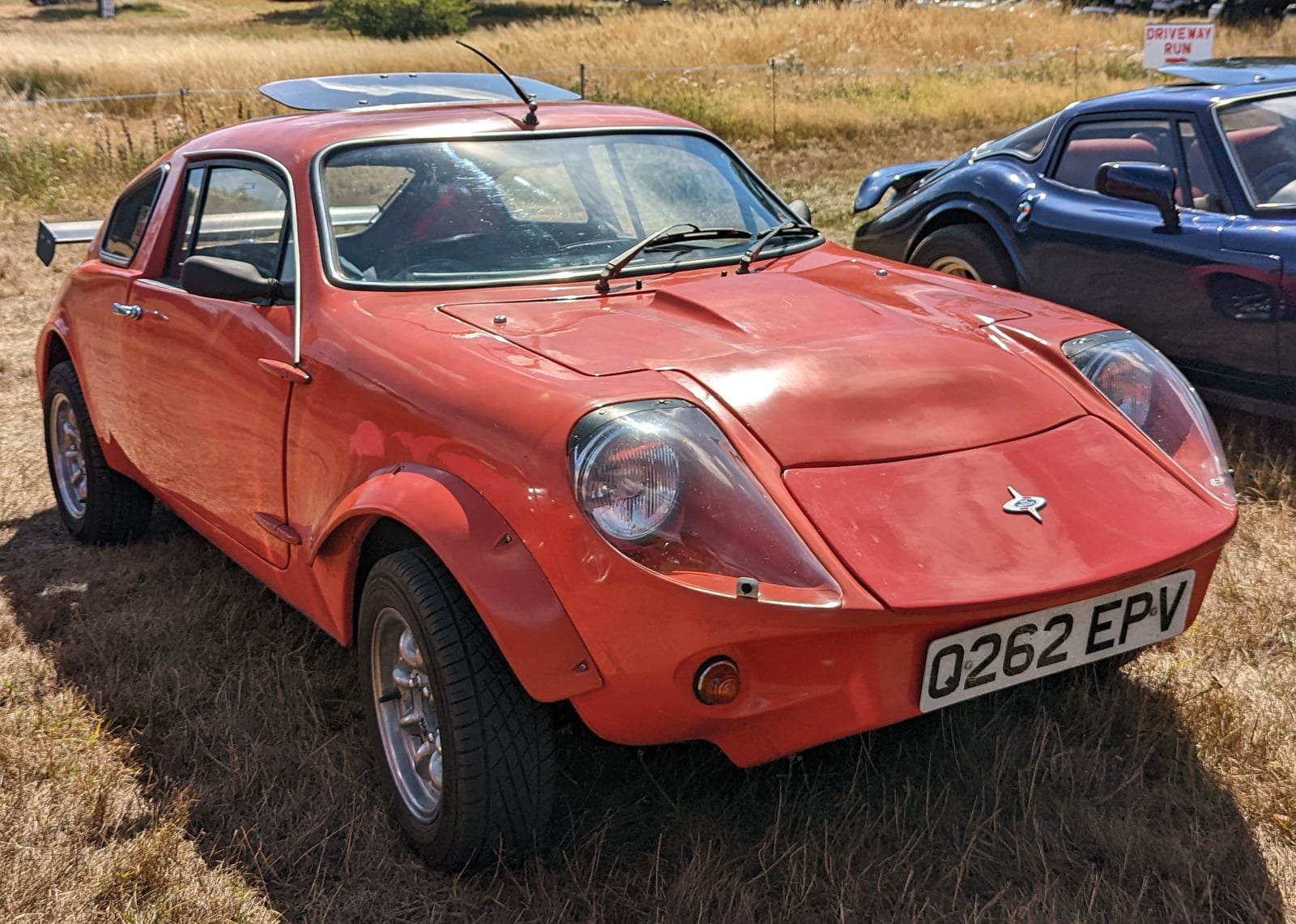 An orange 1990 Marcos Mini Marcos 1300 GT coupe, front three-quarter view