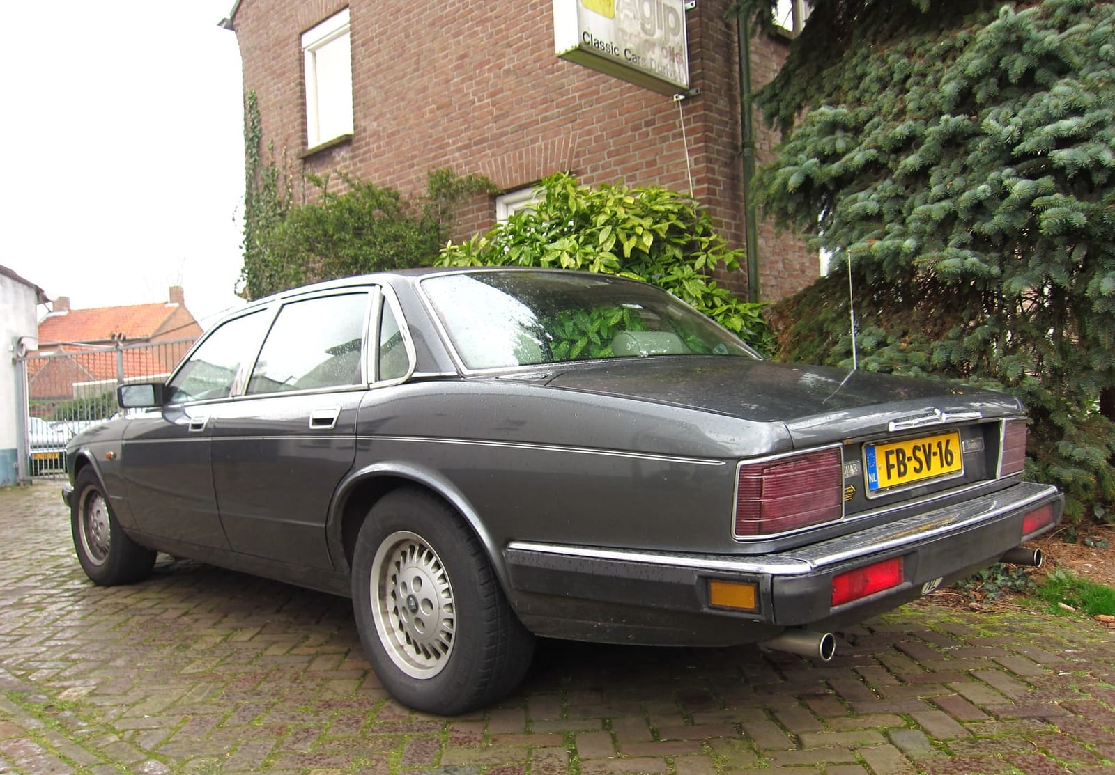 A grey 1992 Jaguar XJ Sovereign 3.2 parked on a gravel driveway, rear three-quarter view