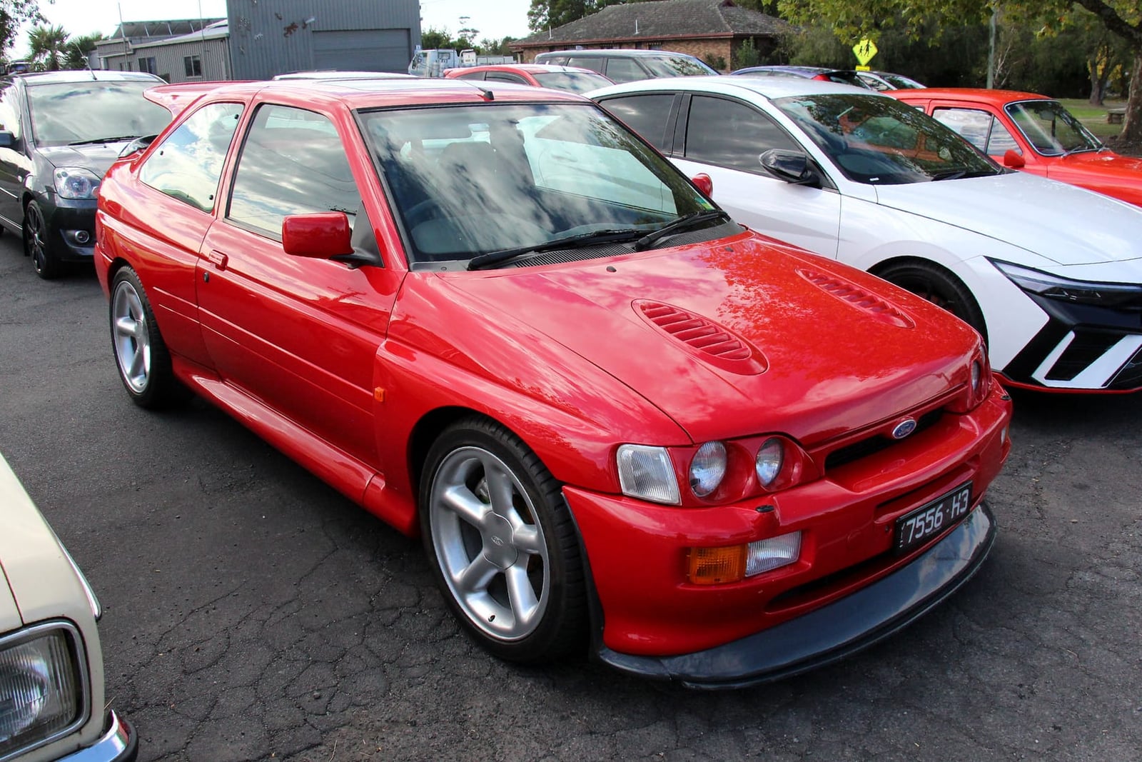 A red 1993 Ford Escort RS Cosworth photographed from the front three-quarter at a car meet